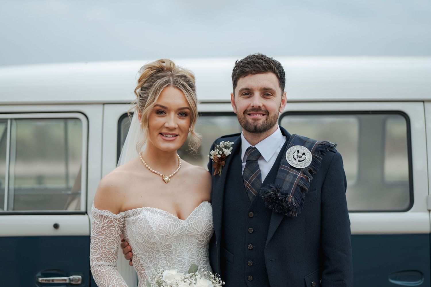Bride and groom share intimate moments during wedding photoshoot with vintage van in background.