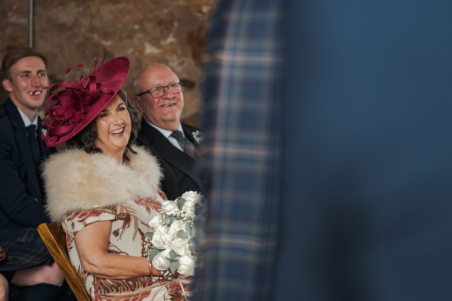 Wedding guests laugh and celebrate together during an emotional reception moment at a rustic stone venue.