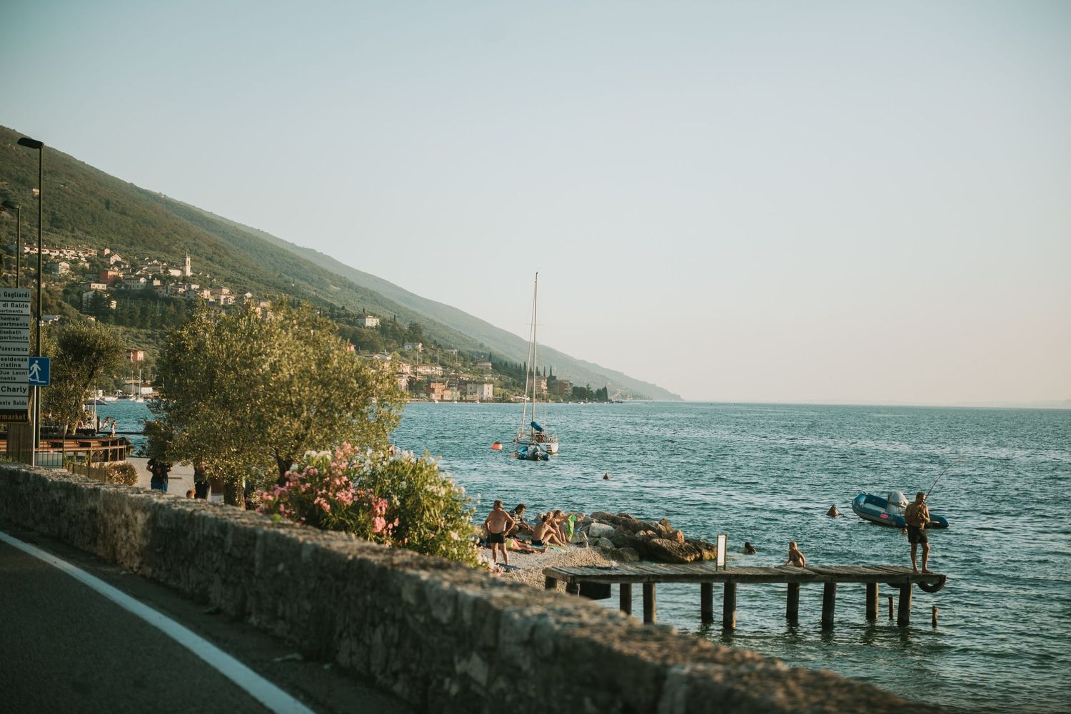 Coastal scene with people enjoying activities along a lakeside promenade.