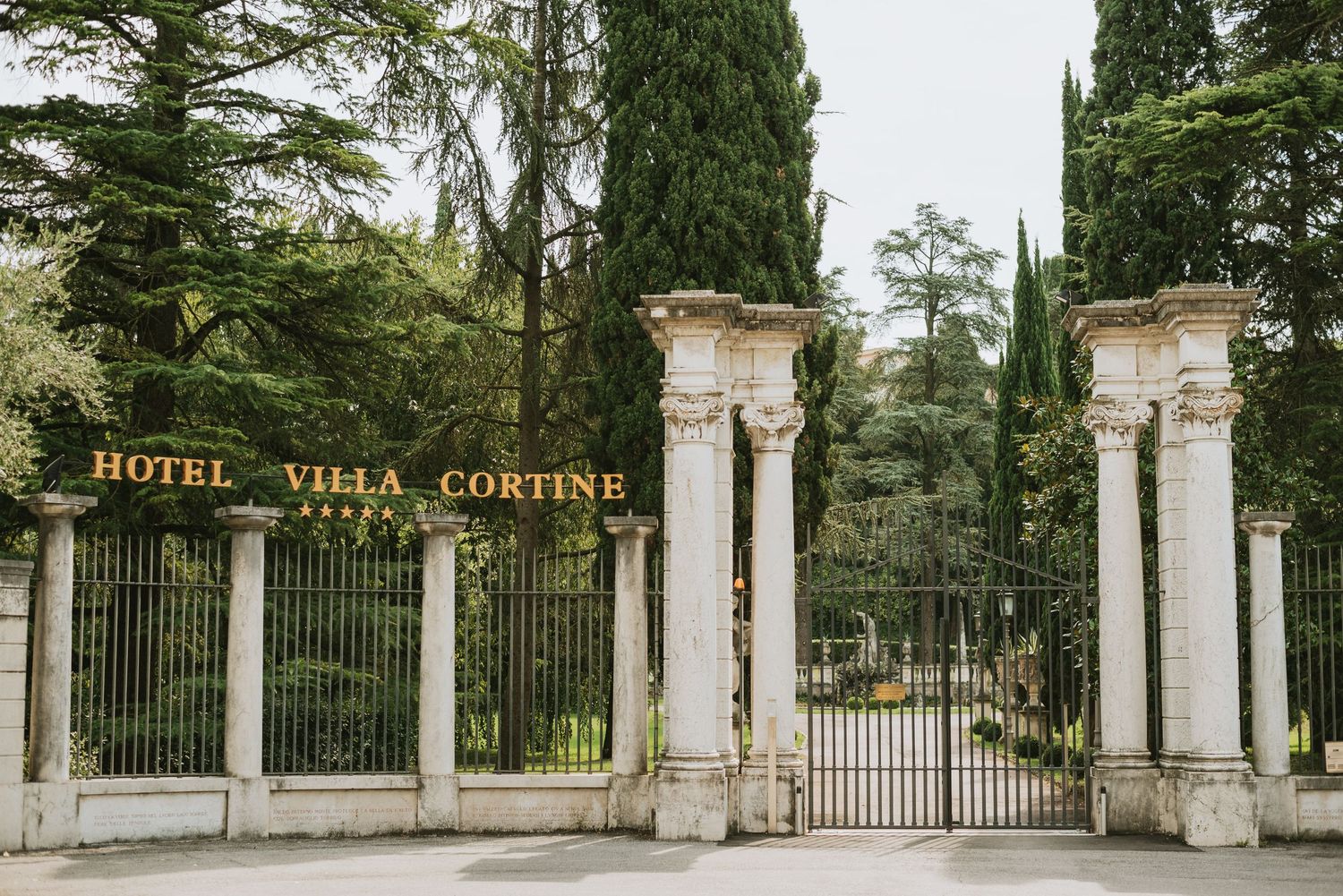 Elegant white stone pillars and iron gates at the entrance of Hotel Villa Cortine.