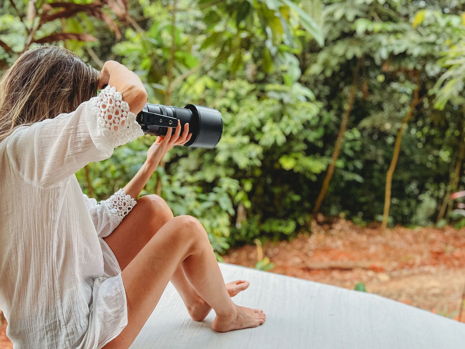 Figure in white dress relaxing on an outdoor porch swing in a garden setting.