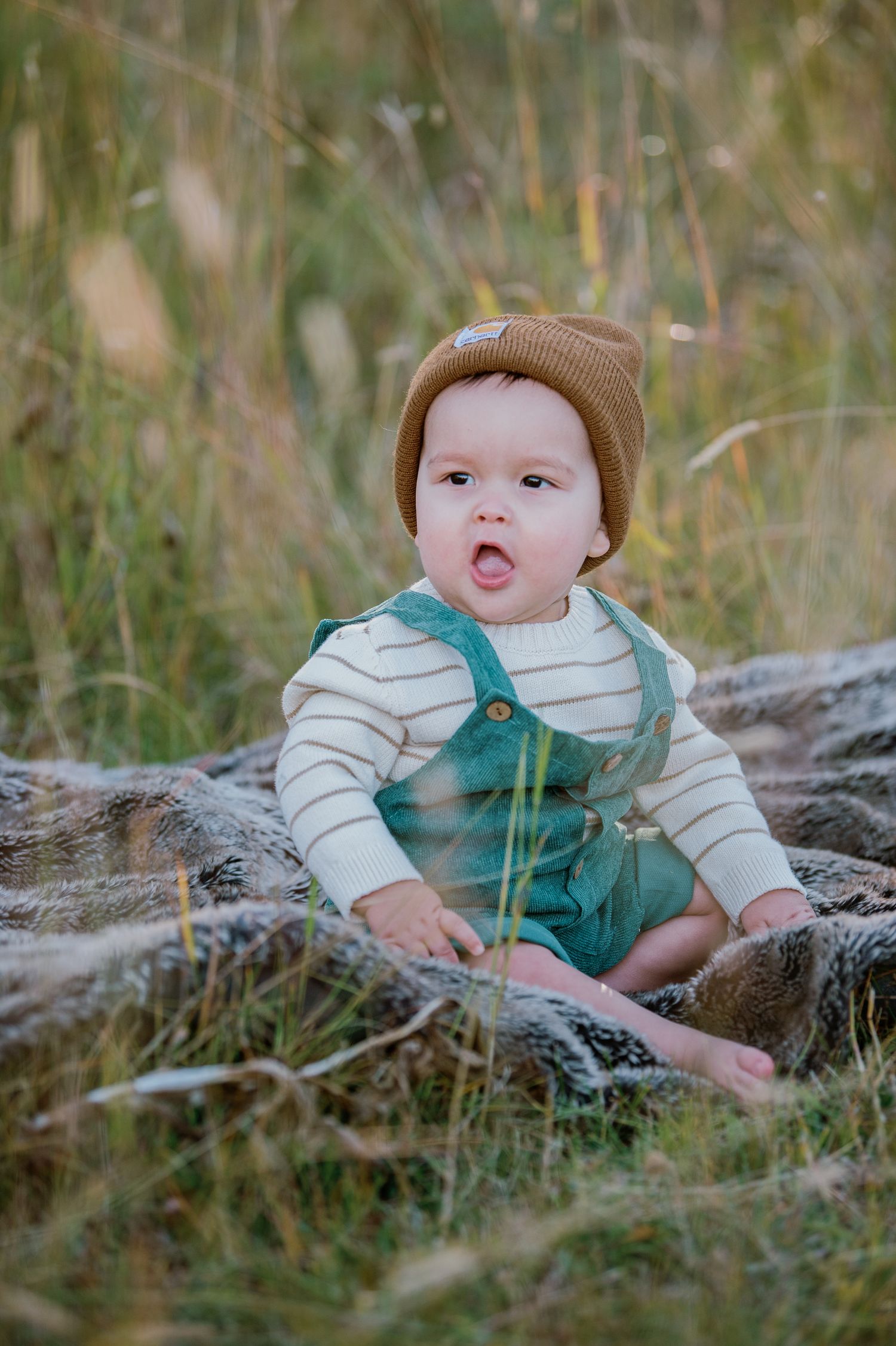 Small figure in green overalls and white shirt lying on wooden log in natural outdoor setting.