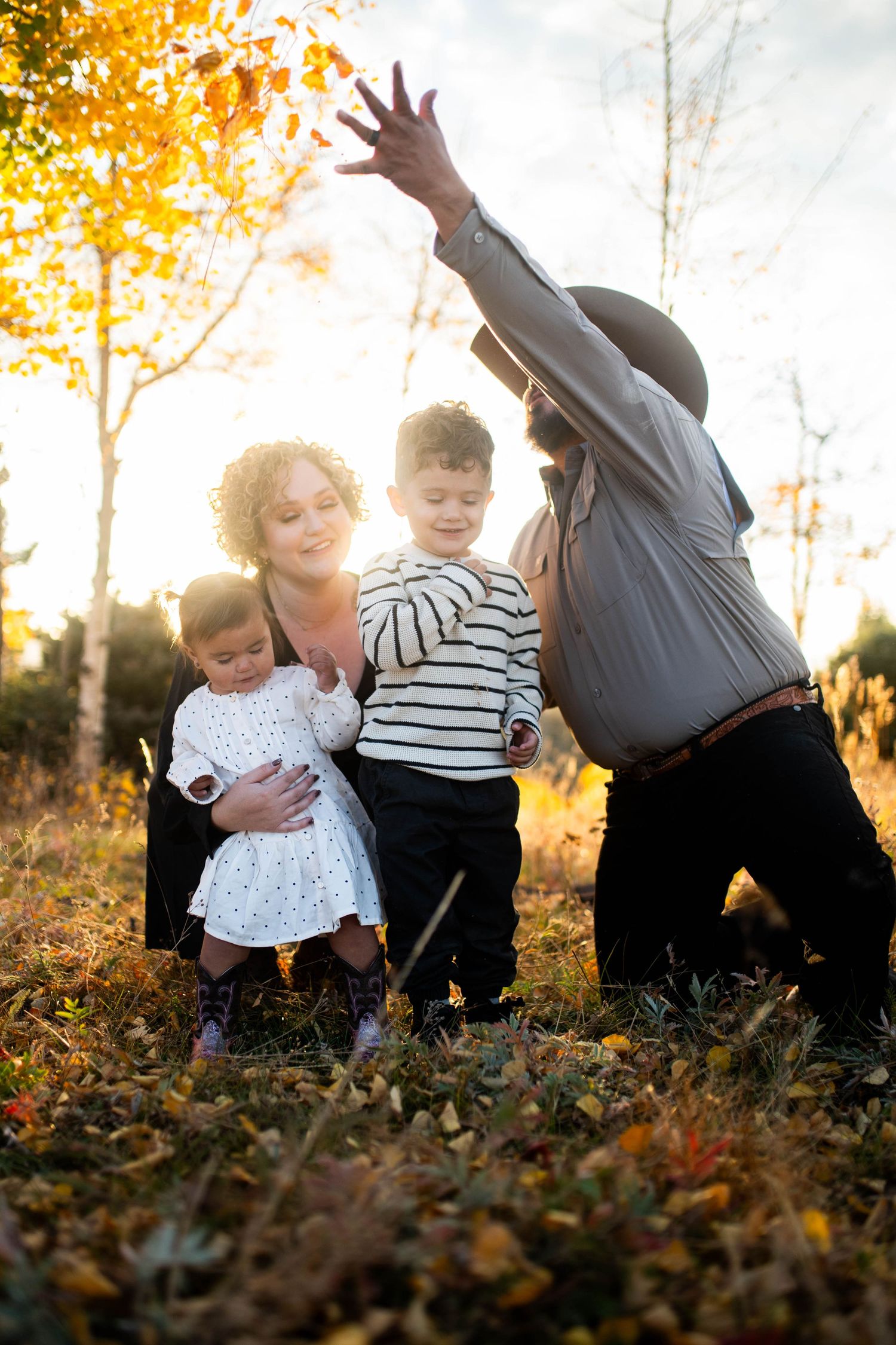 Children playing and falling in autumn leaves during golden hour sunset in a candid outdoor photo series.