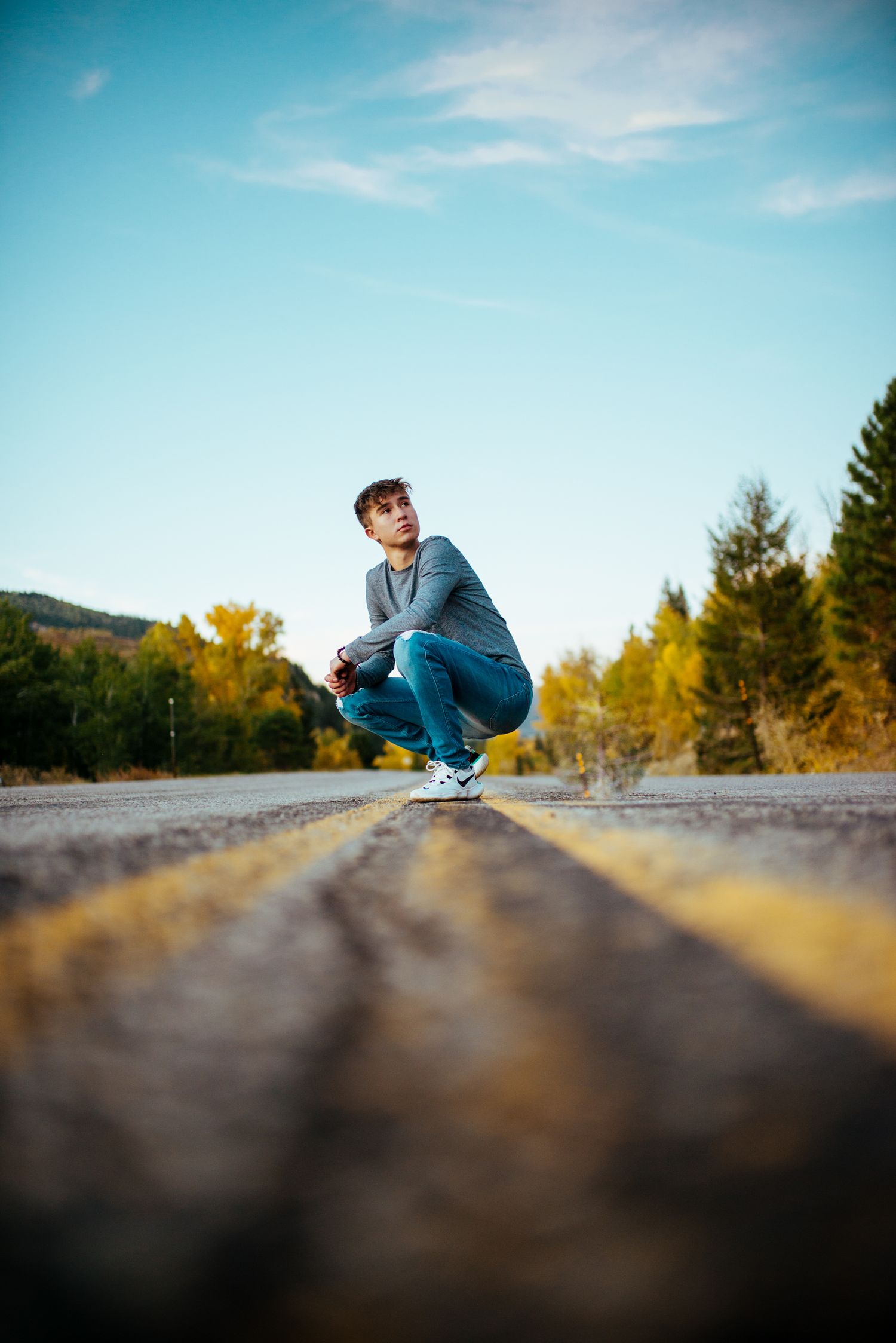 Low angle skateboarding trick captured against blue sky and autumn scenery.