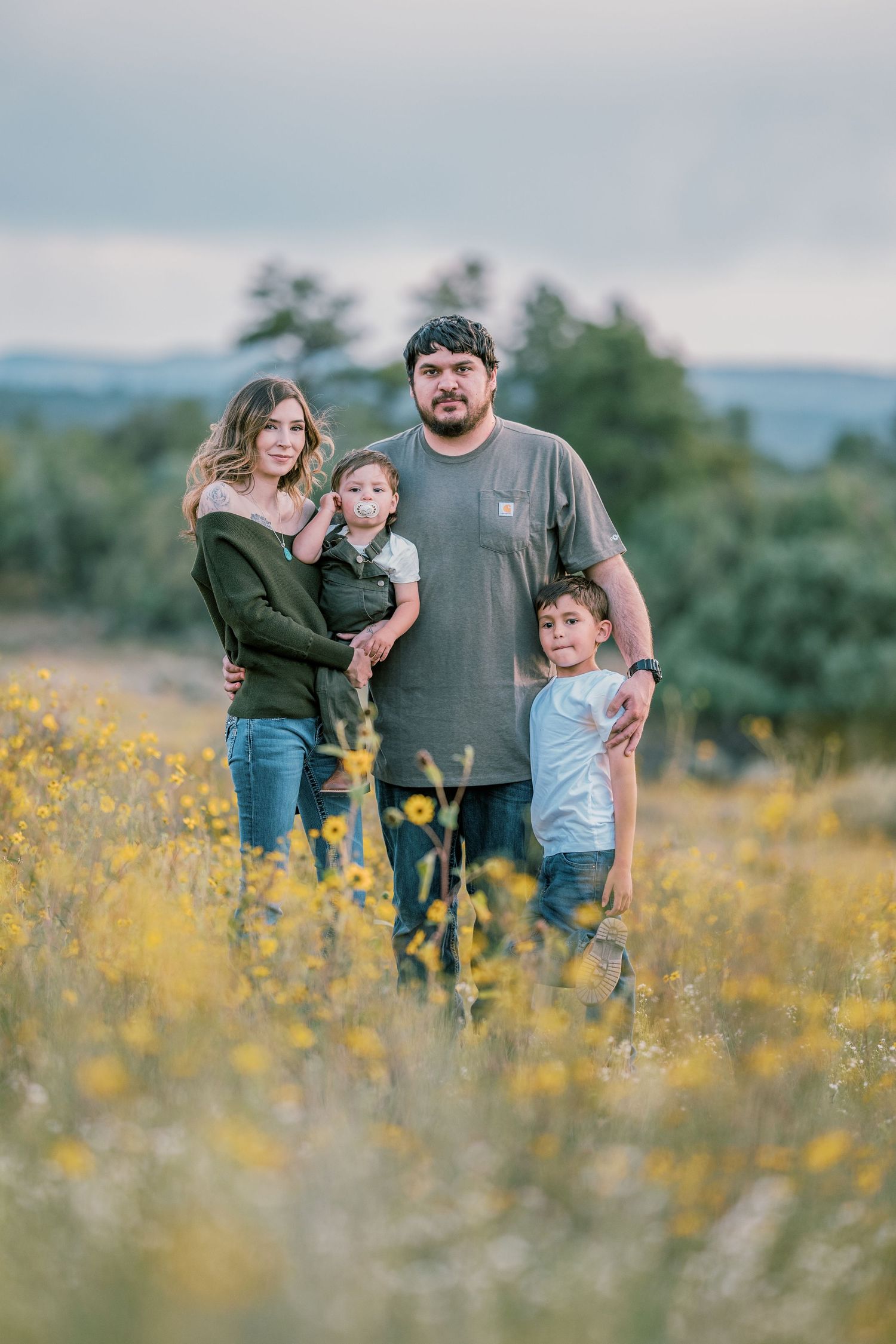 Happy family enjoying outdoor time together among yellow wildflowers at sunset.