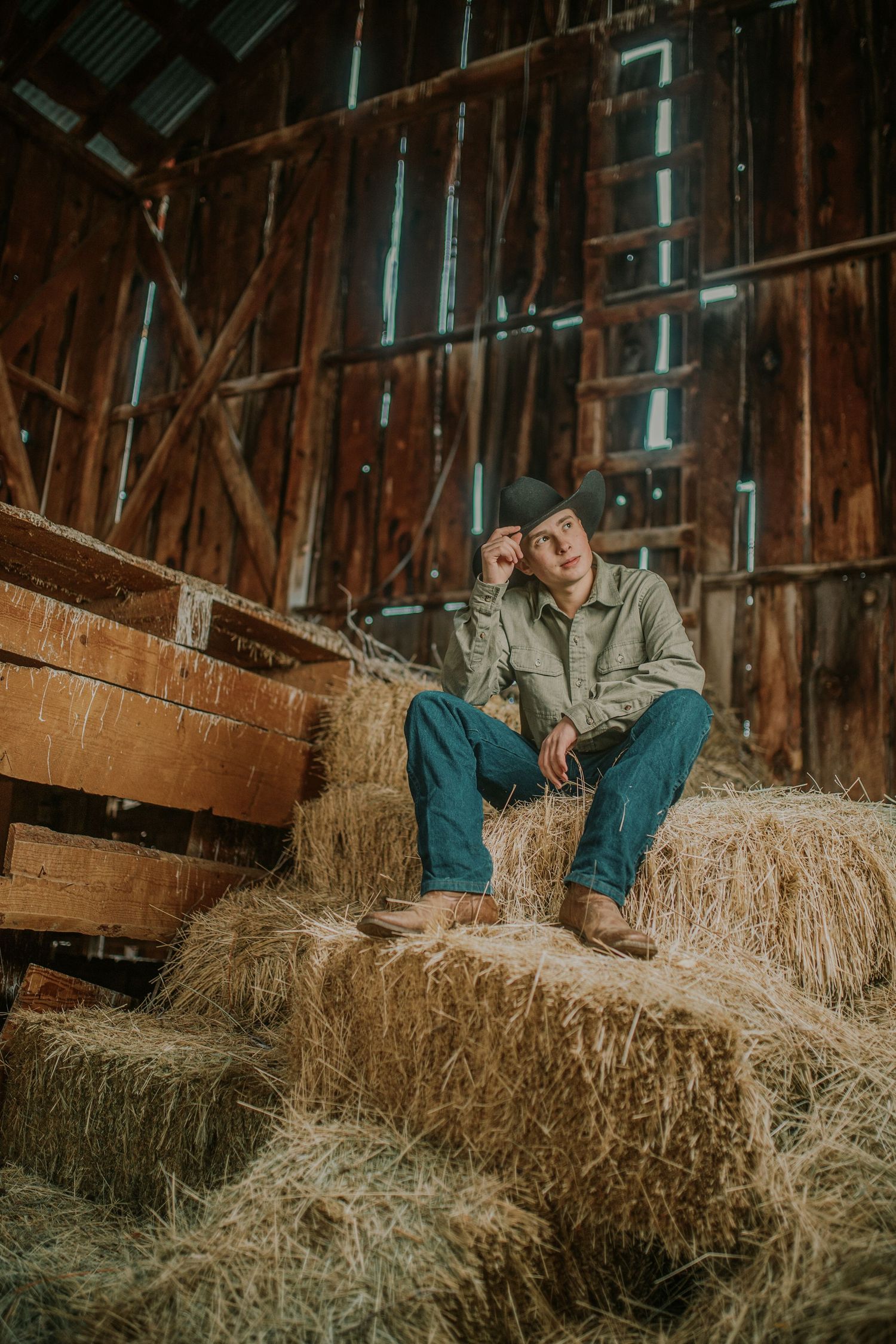 A rustic outdoor portrait on hay bales inside a wooden barn with natural lighting streaming through slats.