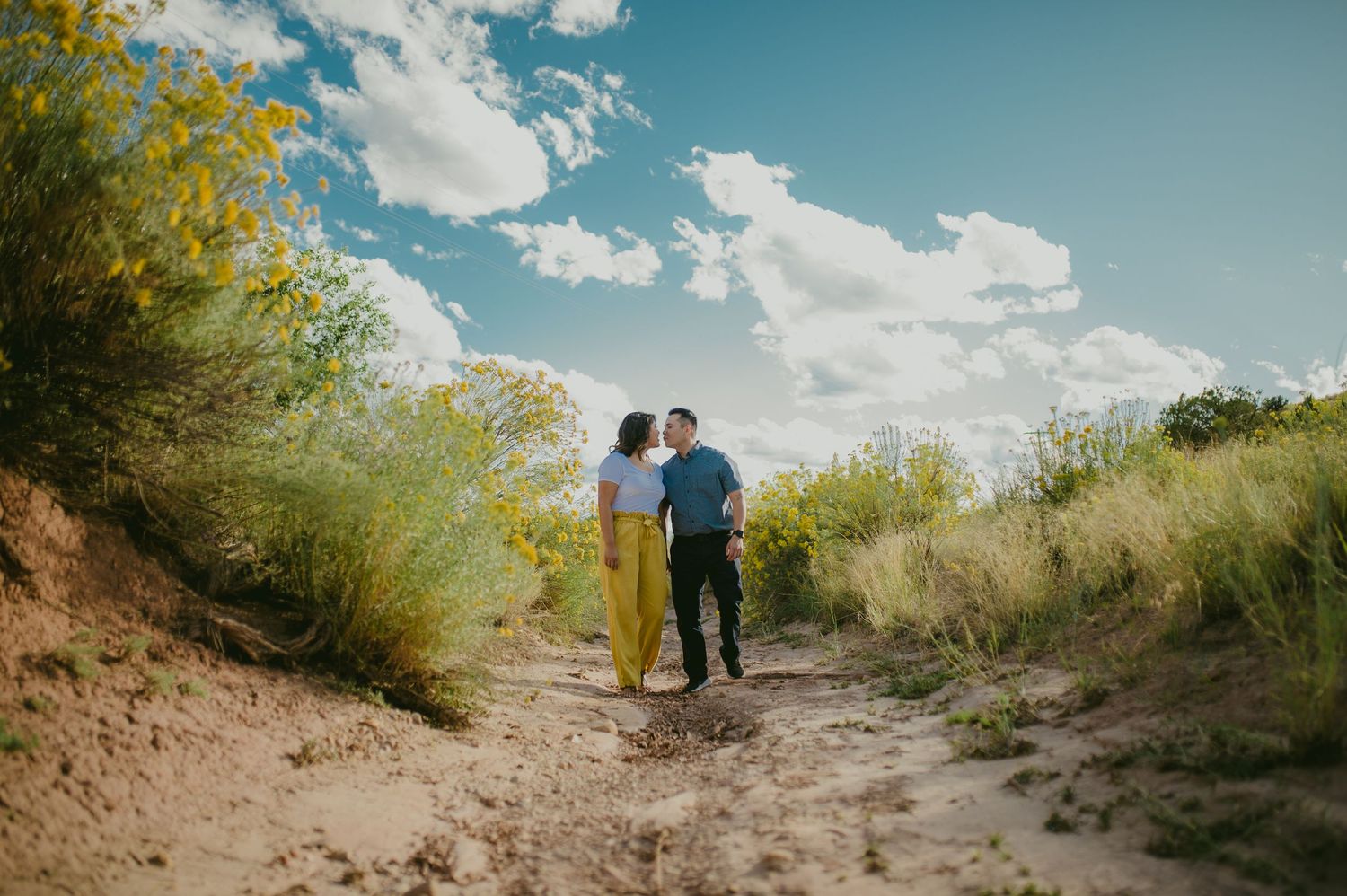 Distant couple walking together on a desert trail under blue skies.
