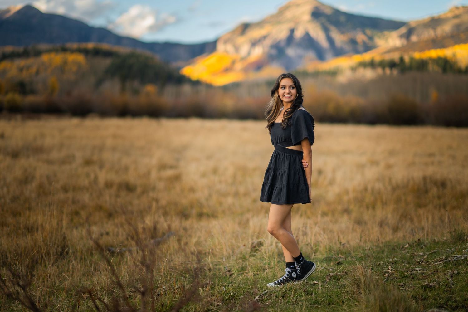 A scenic mountain landscape with golden sunlight illuminating the peaks and grassy fields during sunset.