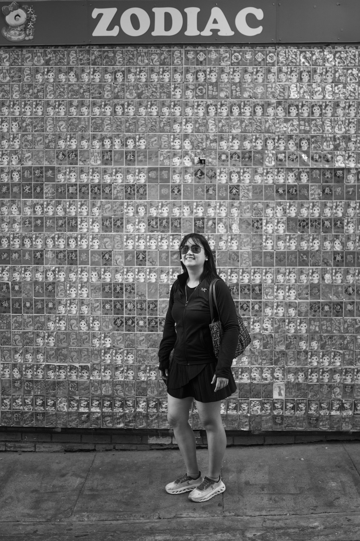 Black and white photo series showing figure posed against wall covered in repetitive grid pattern artwork.