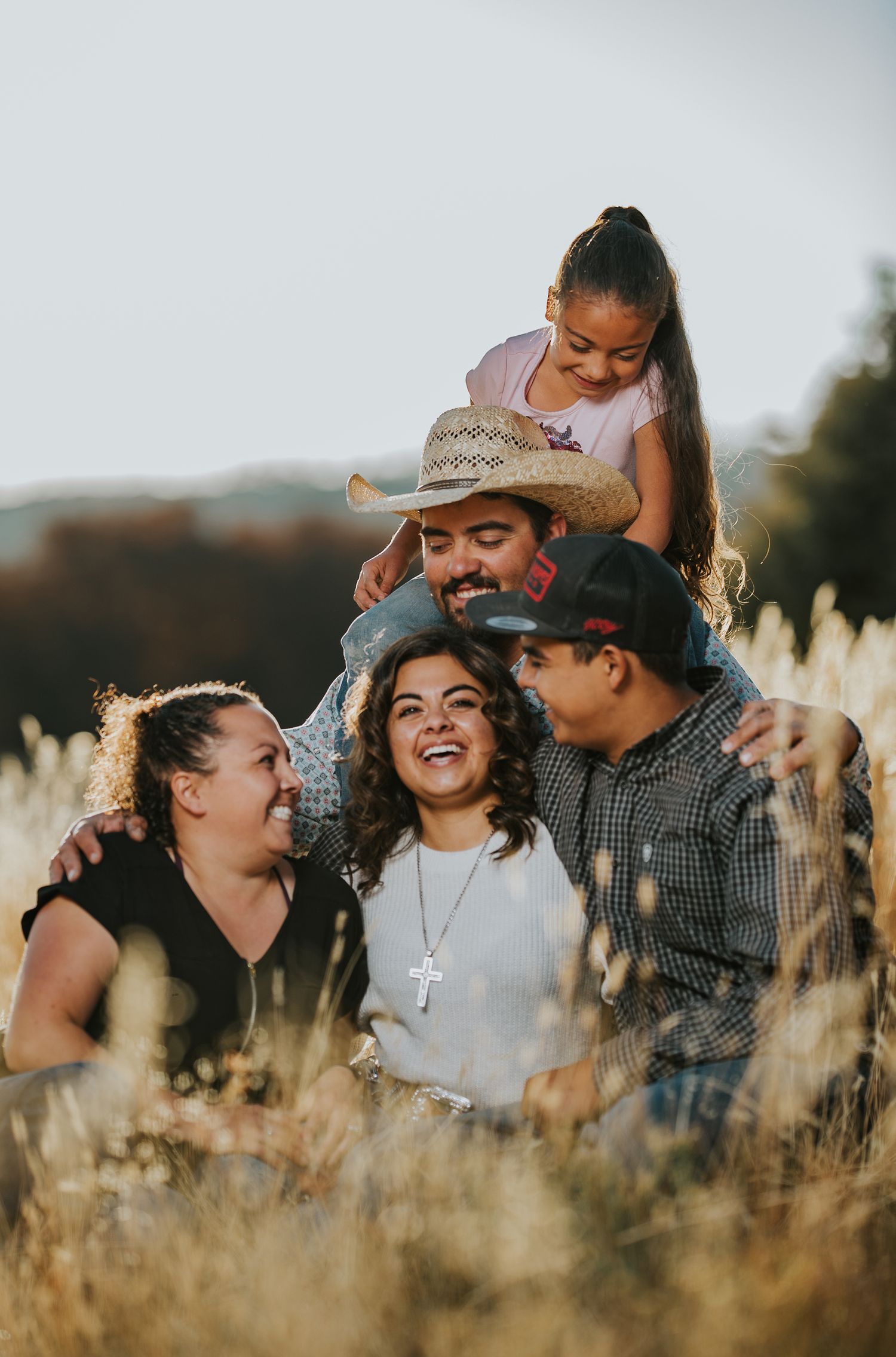 Candid family moment showing playful interactions in tall grass during golden hour.