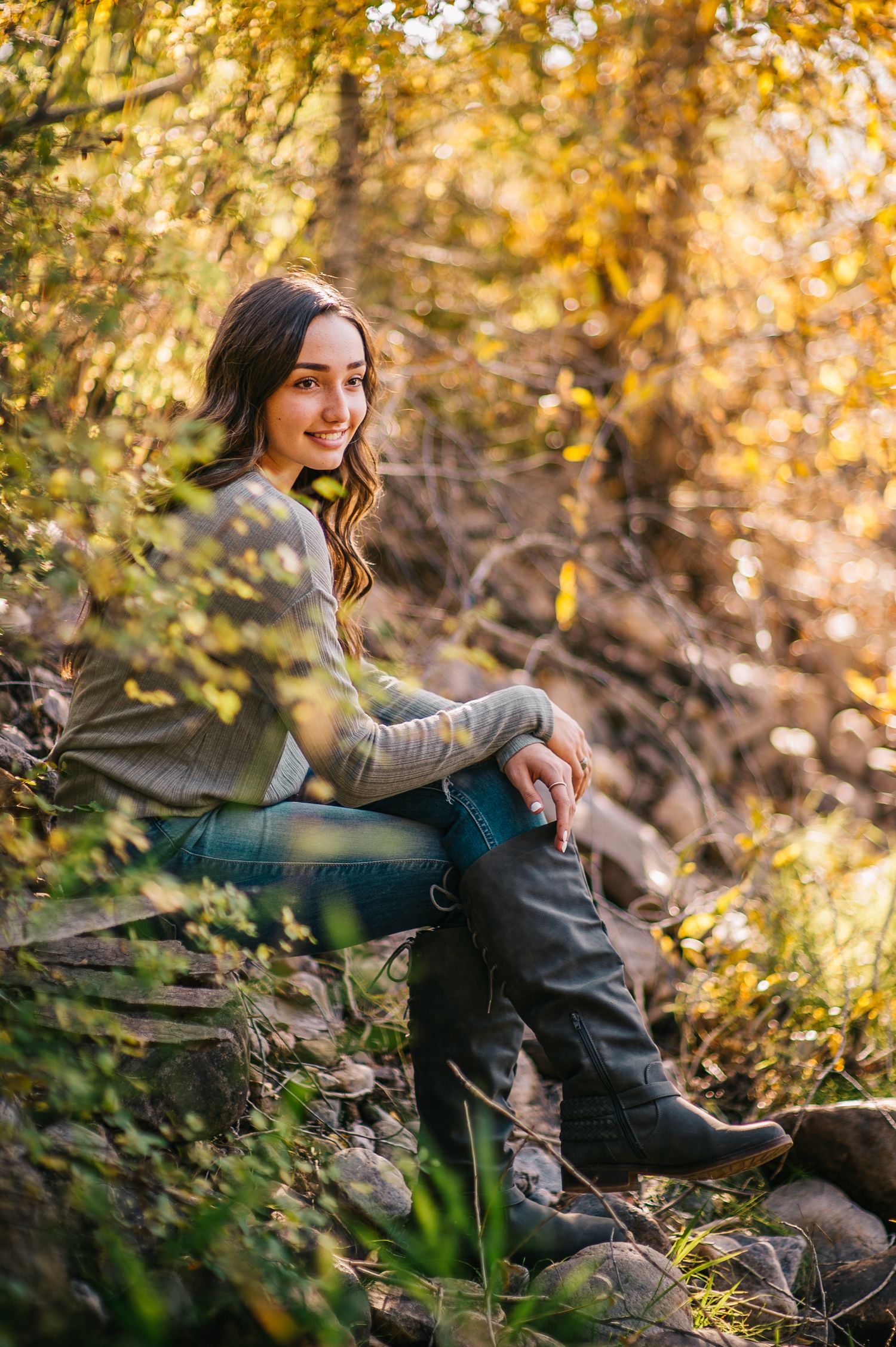 Candid autumn photoshoot with subject lounging among fallen leaves and natural scenery.