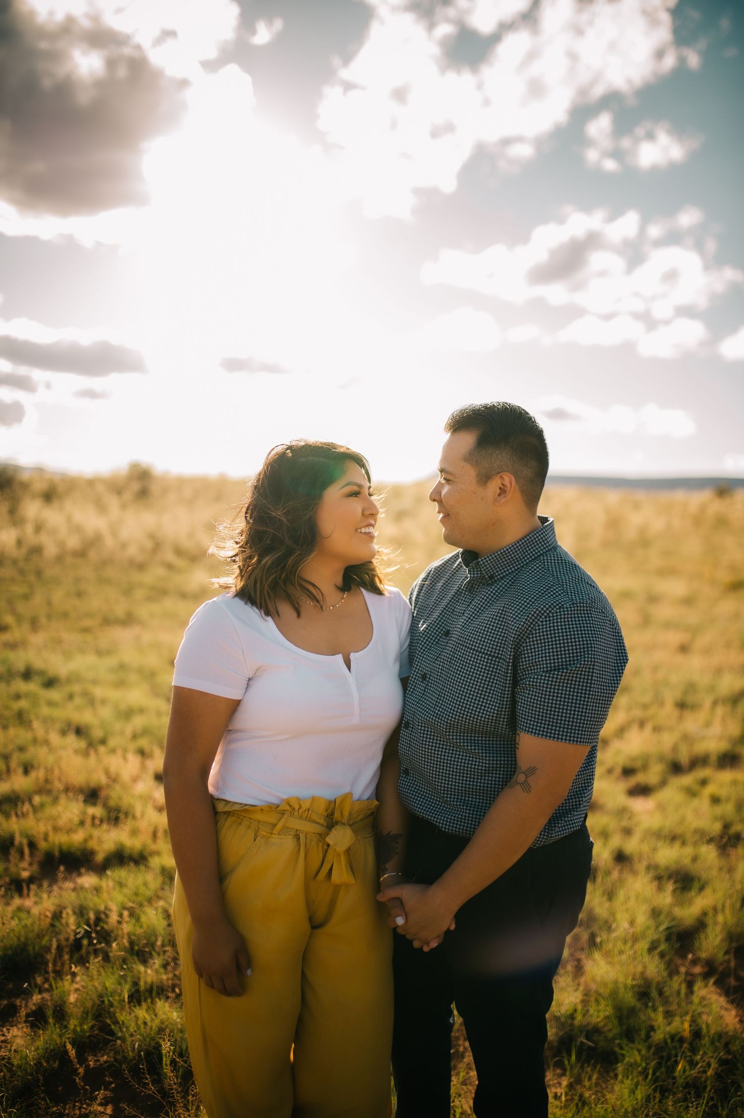 A romantic couple shares tender moments at sunset in a golden field of grass.