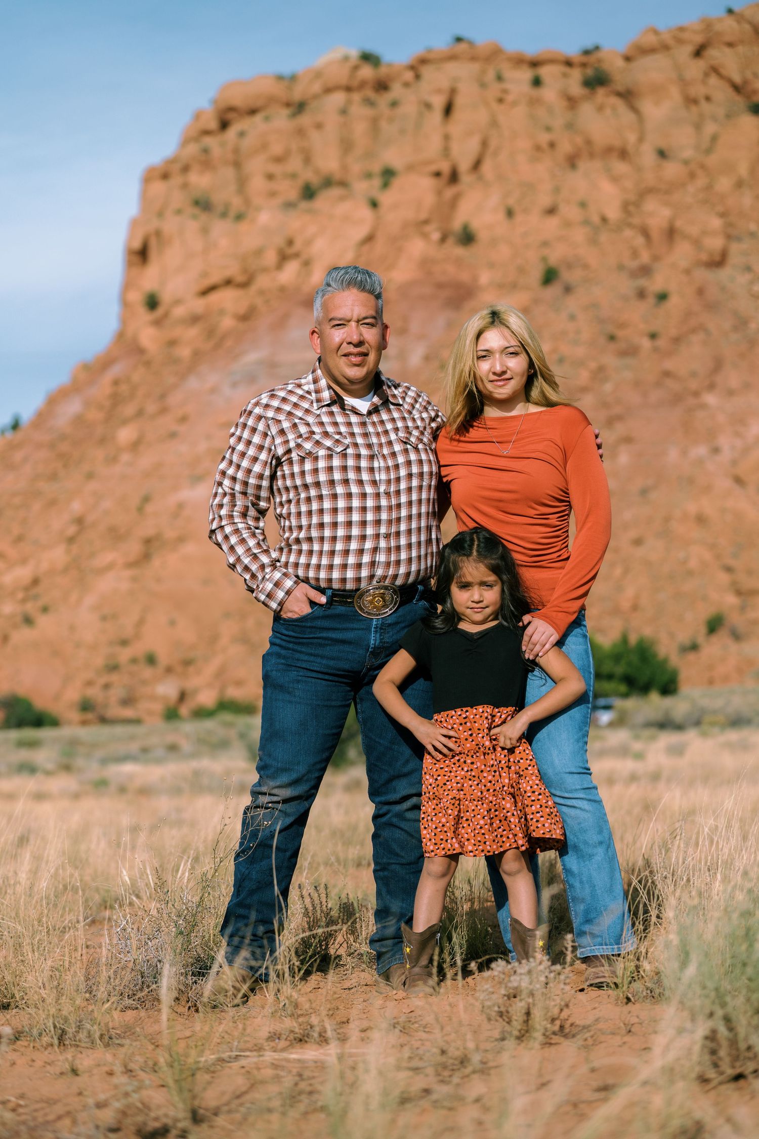 Family poses together against scenic red rock formations in outdoor portrait series at sunset.