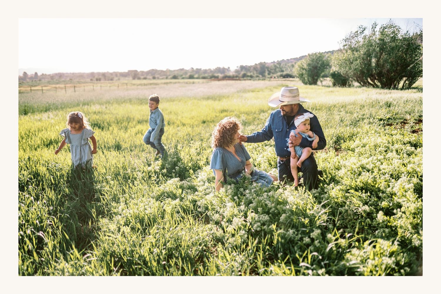 Family playing in a sunny green meadow field together.