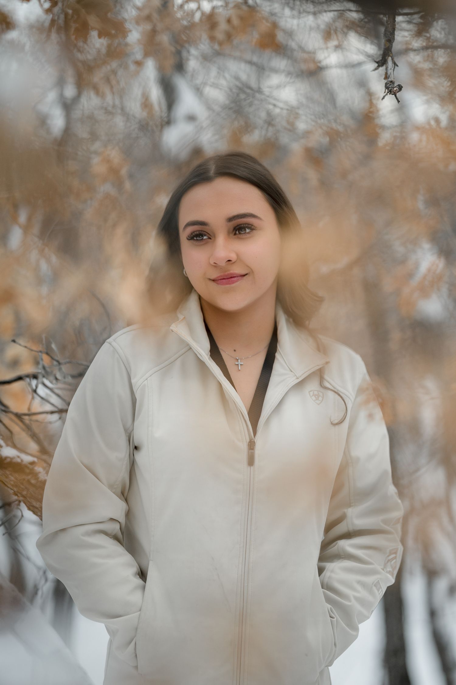 A winter portrait in soft lighting featuring a white jacket against a backdrop of golden autumn leaves.