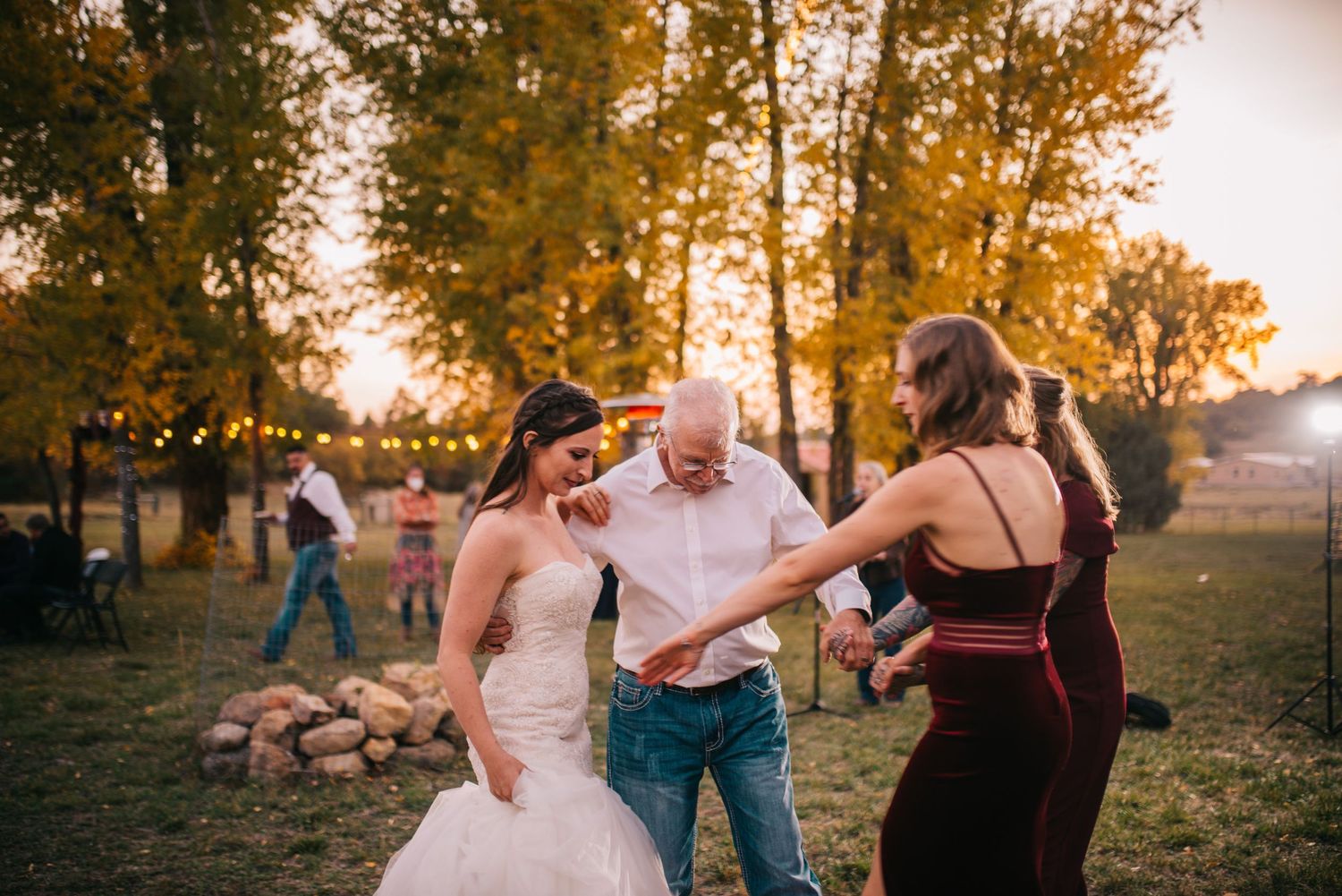 Wedding reception guests dancing outdoors during sunset celebration.