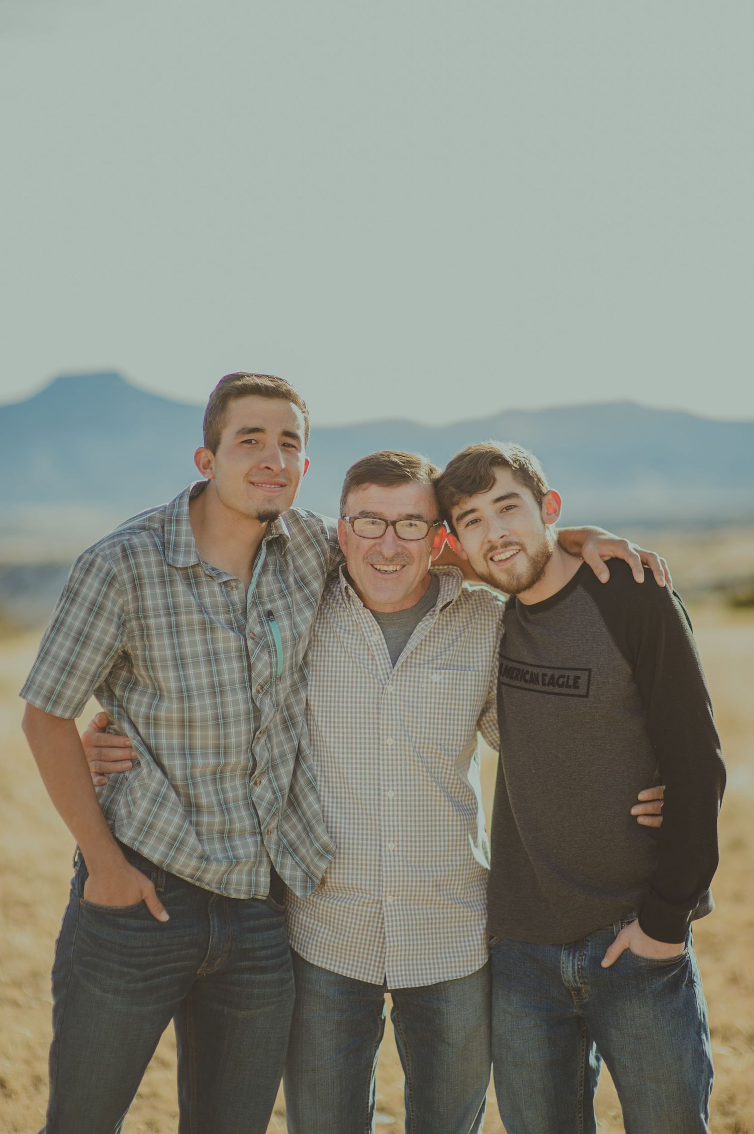 Father with his two adult sons standing together in Abiquiú's desert landscape — warm, natural light photo by Quiet Light by The Amoras.