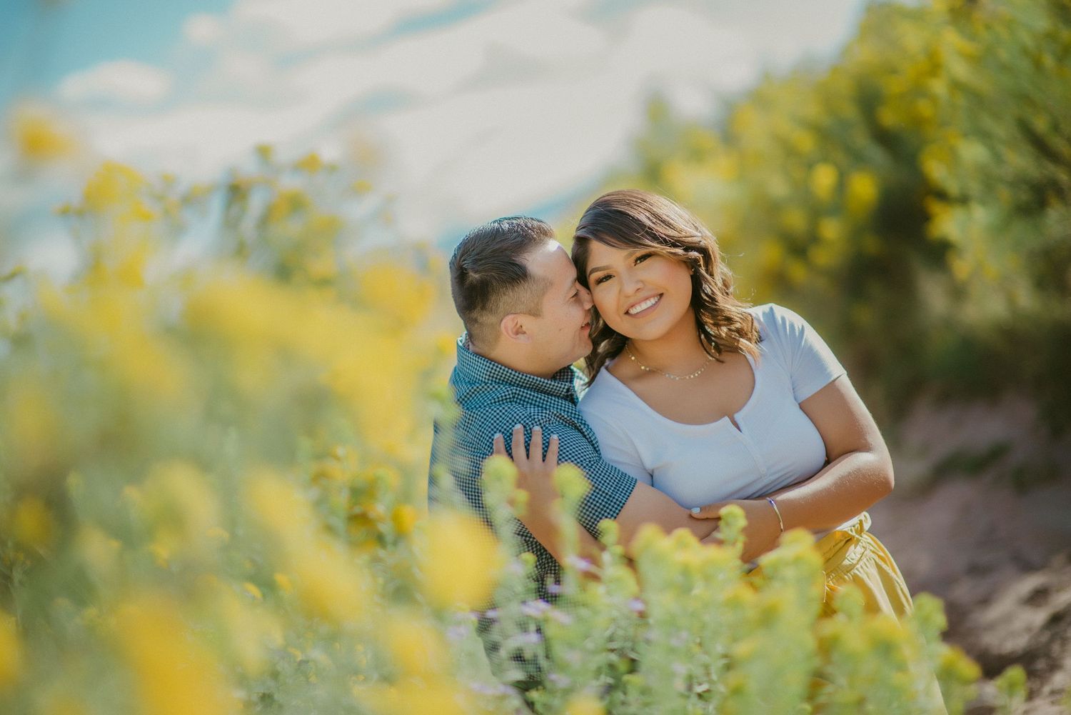A couple shares romantic moments among yellow wildflowers during golden hour.