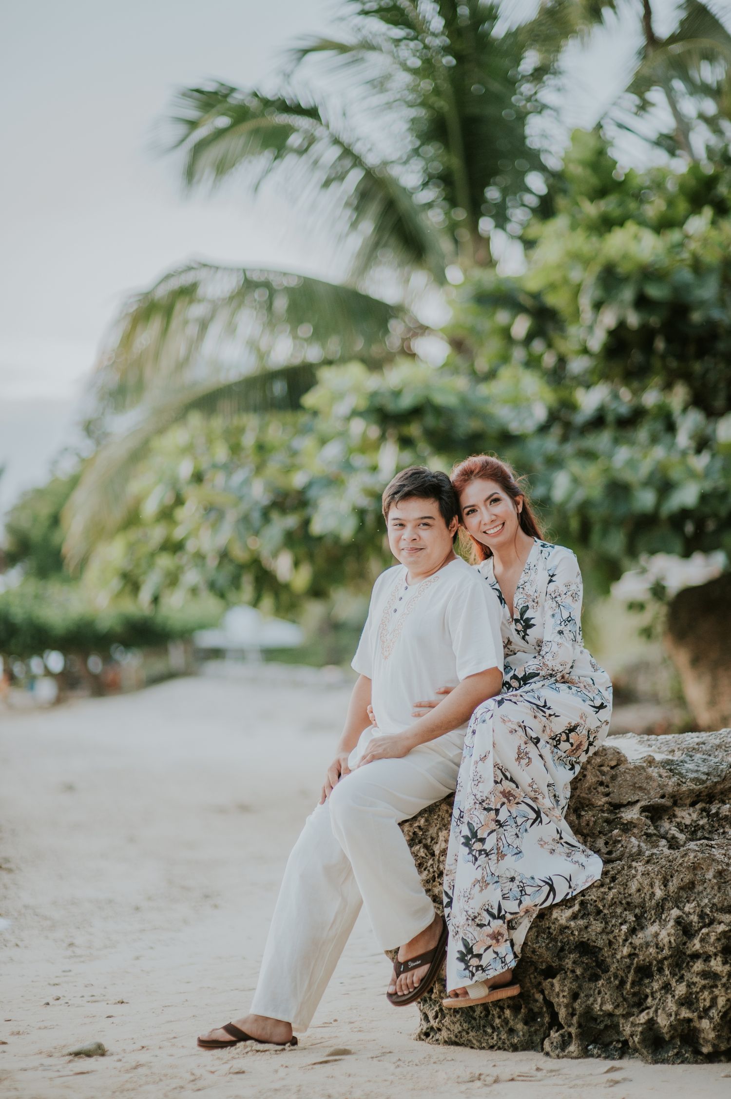 A tropical beach setting with palm trees and rocks for a romantic photoshoot.