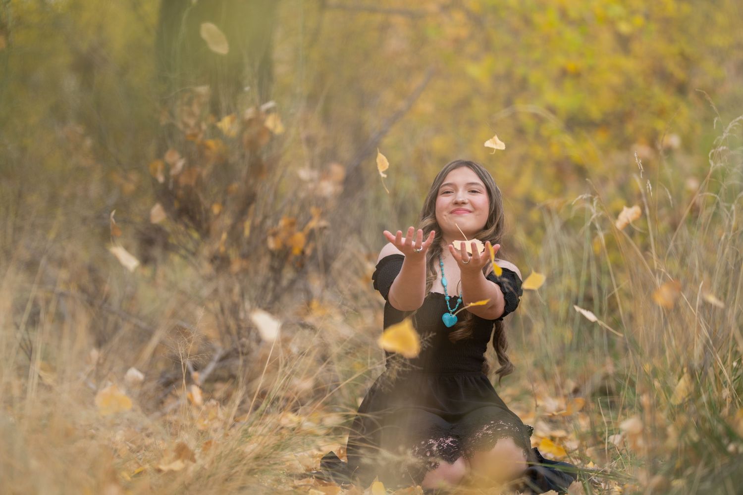 A joyful autumn scene with falling leaves and golden light in a natural outdoor setting.