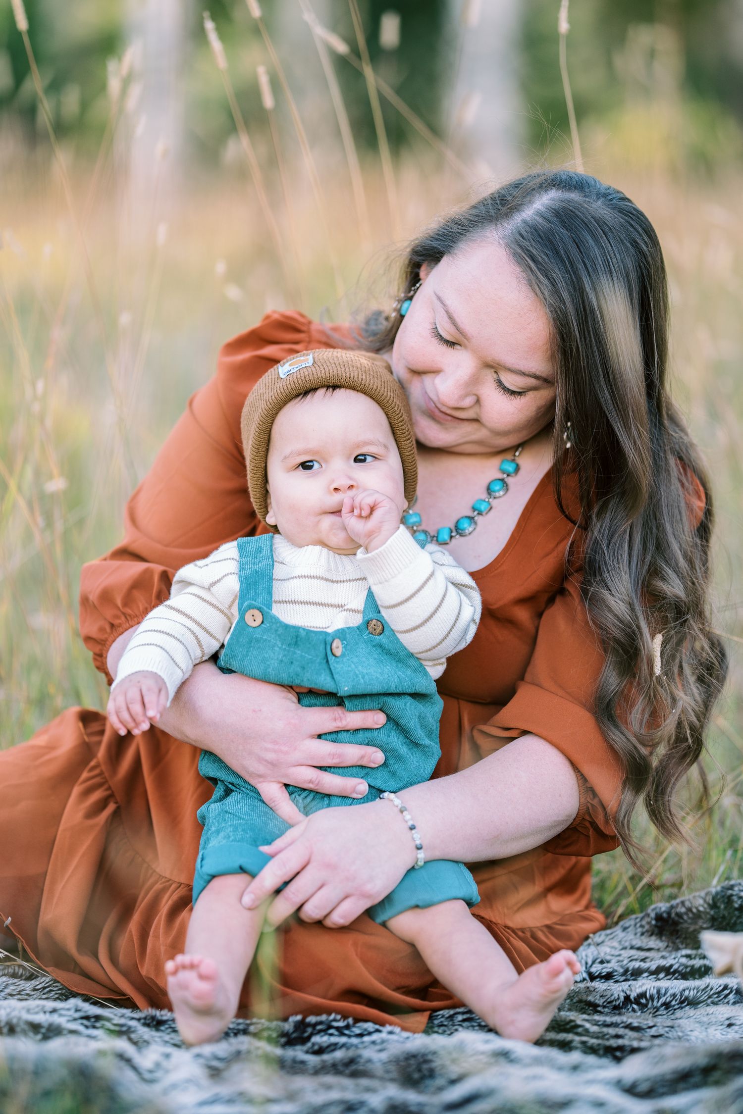 A tender outdoor portrait of a parent and baby in a rustic setting.