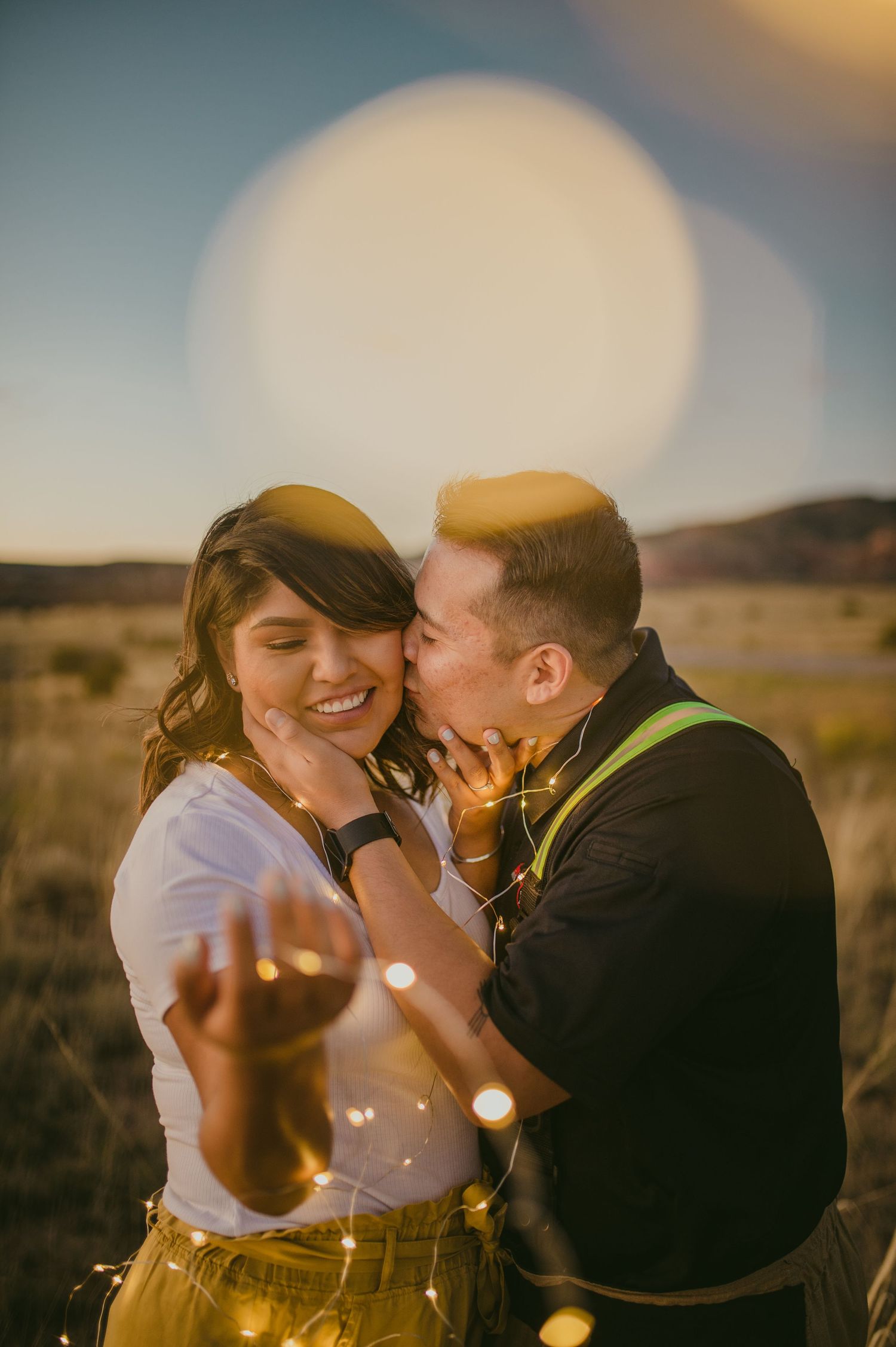 A couple shares joyful moments during their sunset photoshoot with beautiful bokeh effects.