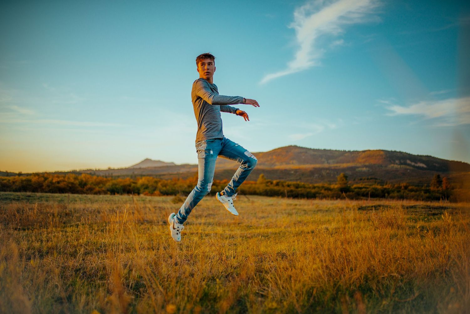 Dynamic action shot of jumping figure in open field with mountains in background.