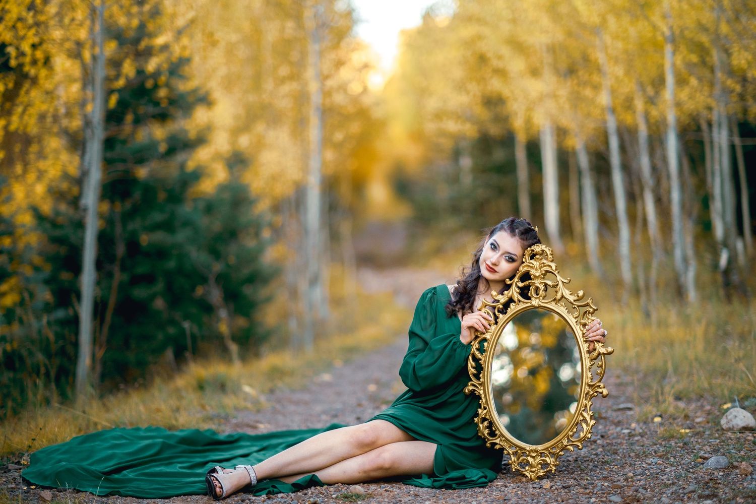 Romantic autumn engagement photoshoot in a golden aspen forest during sunset with couple in green attire.