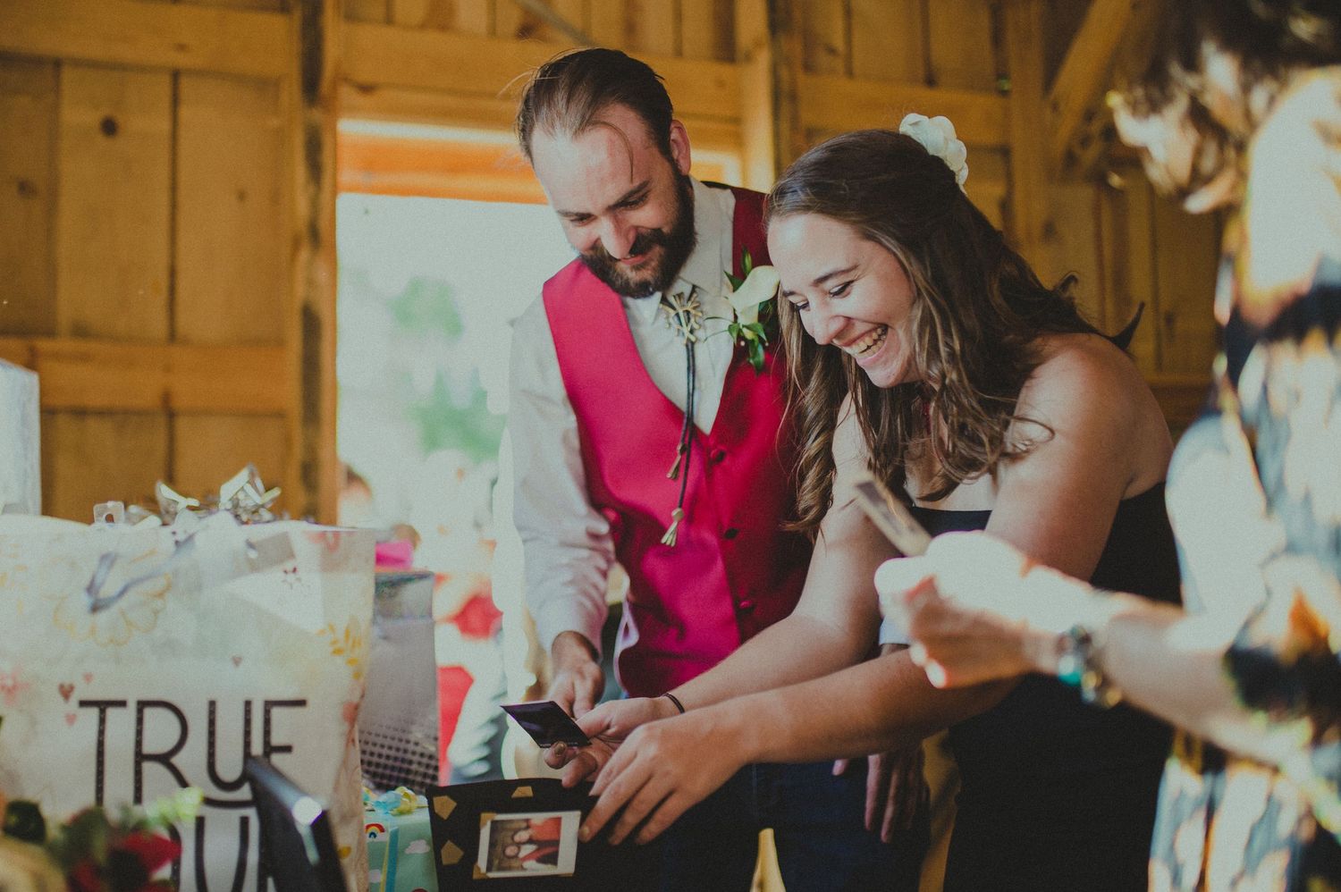 Joyful moment at rustic wedding reception with guests opening gifts.