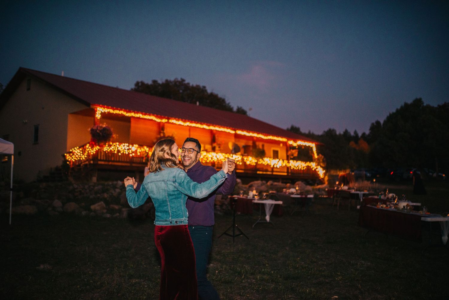 Celebration at dusk outside venue with string lights illuminating the building.