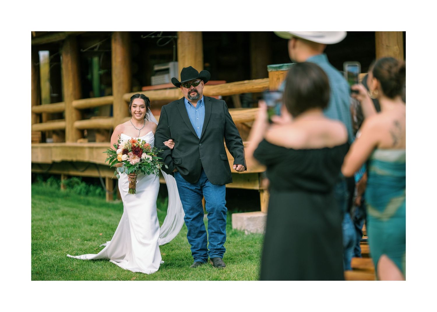 Outdoor wedding ceremony moment with couple sitting in white chairs on a grass lawn.