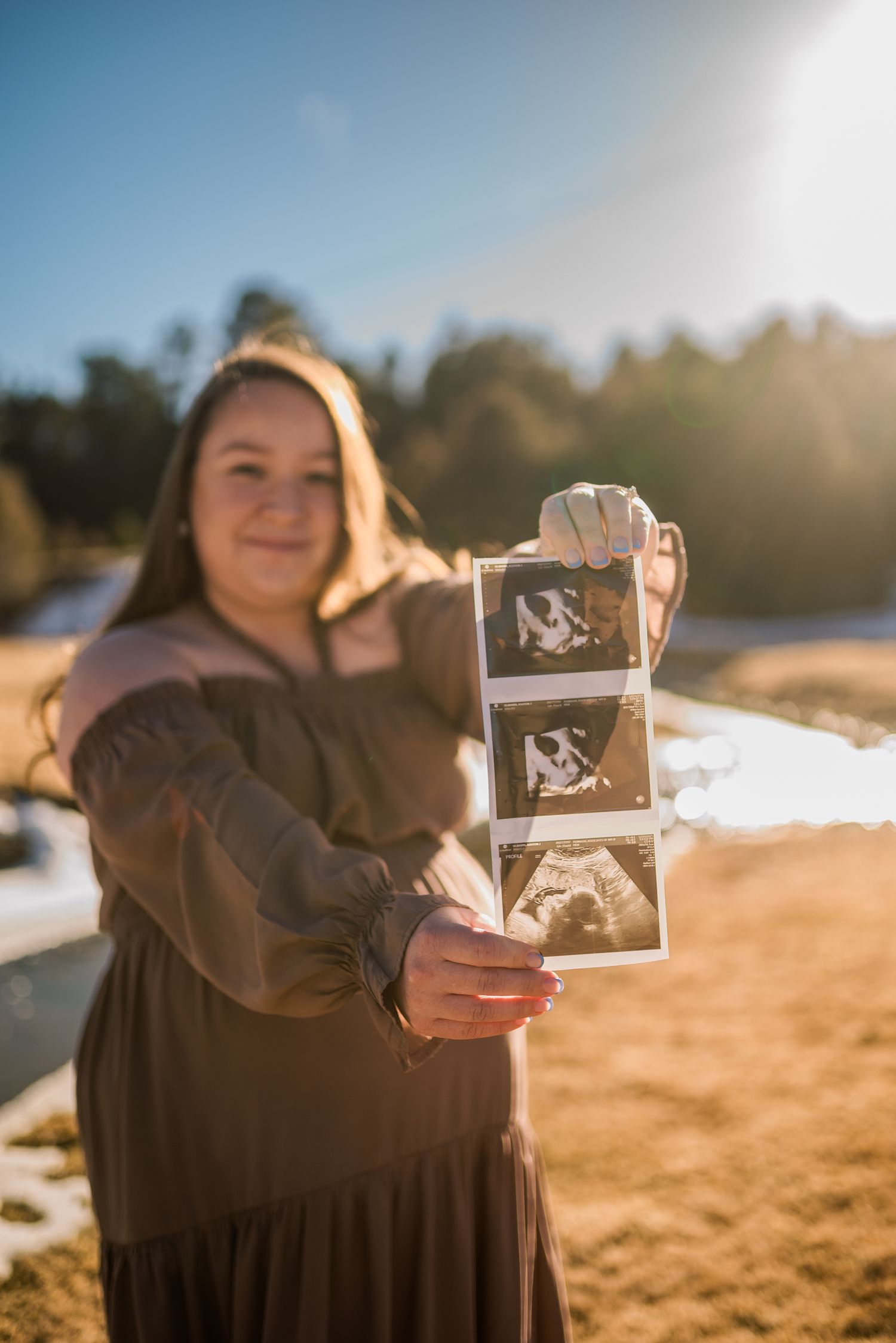 A series of photos showing someone in a brown sweater holding up ultrasound photos at sunset on a beach.
