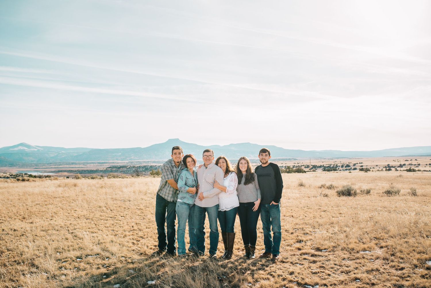Parents with two sons and two daughters embracing in the open desert plains of Abiquiú — serene and heartfelt image by The Amoras.