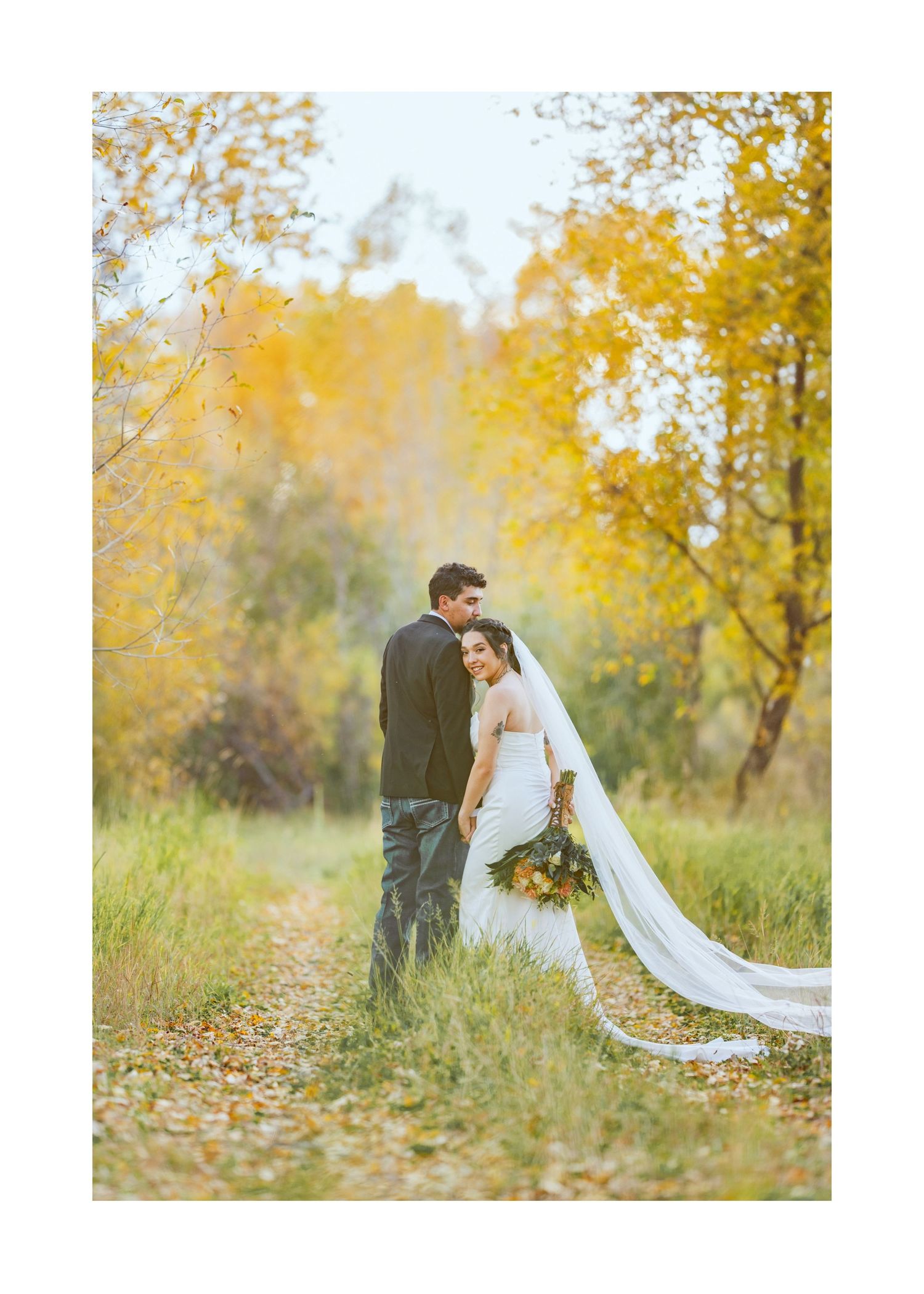 Newlywed couple shares intimate moments among golden autumn foliage in a romantic outdoor photoshoot.