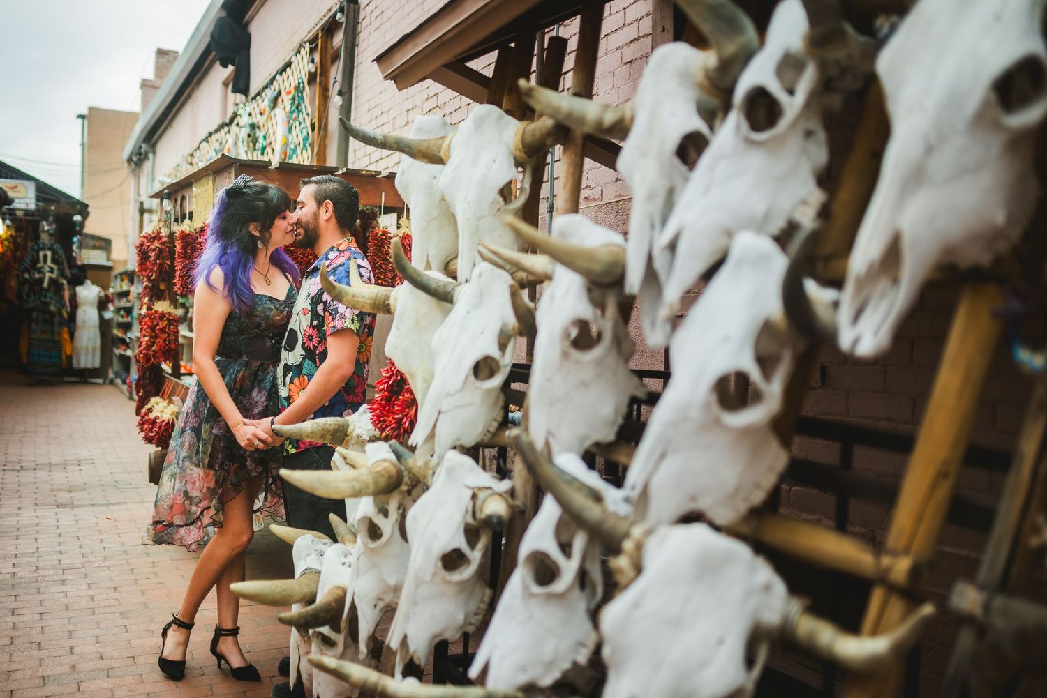 Couple sharing a romantic moment among bull skulls and Southwest decor at an outdoor market.