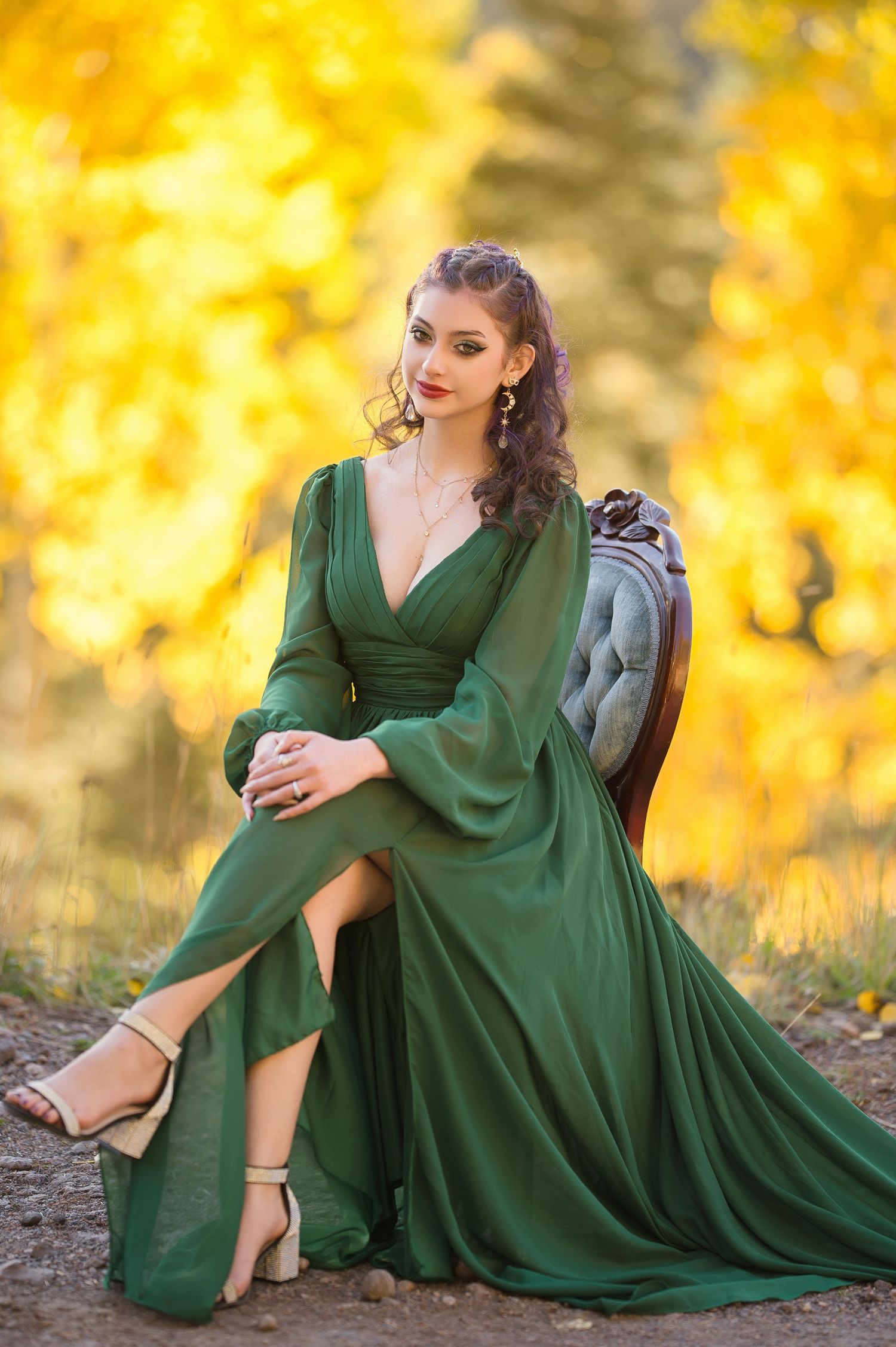 Elegant emerald green flowing dress photographed against vibrant autumn foliage in a nature setting.