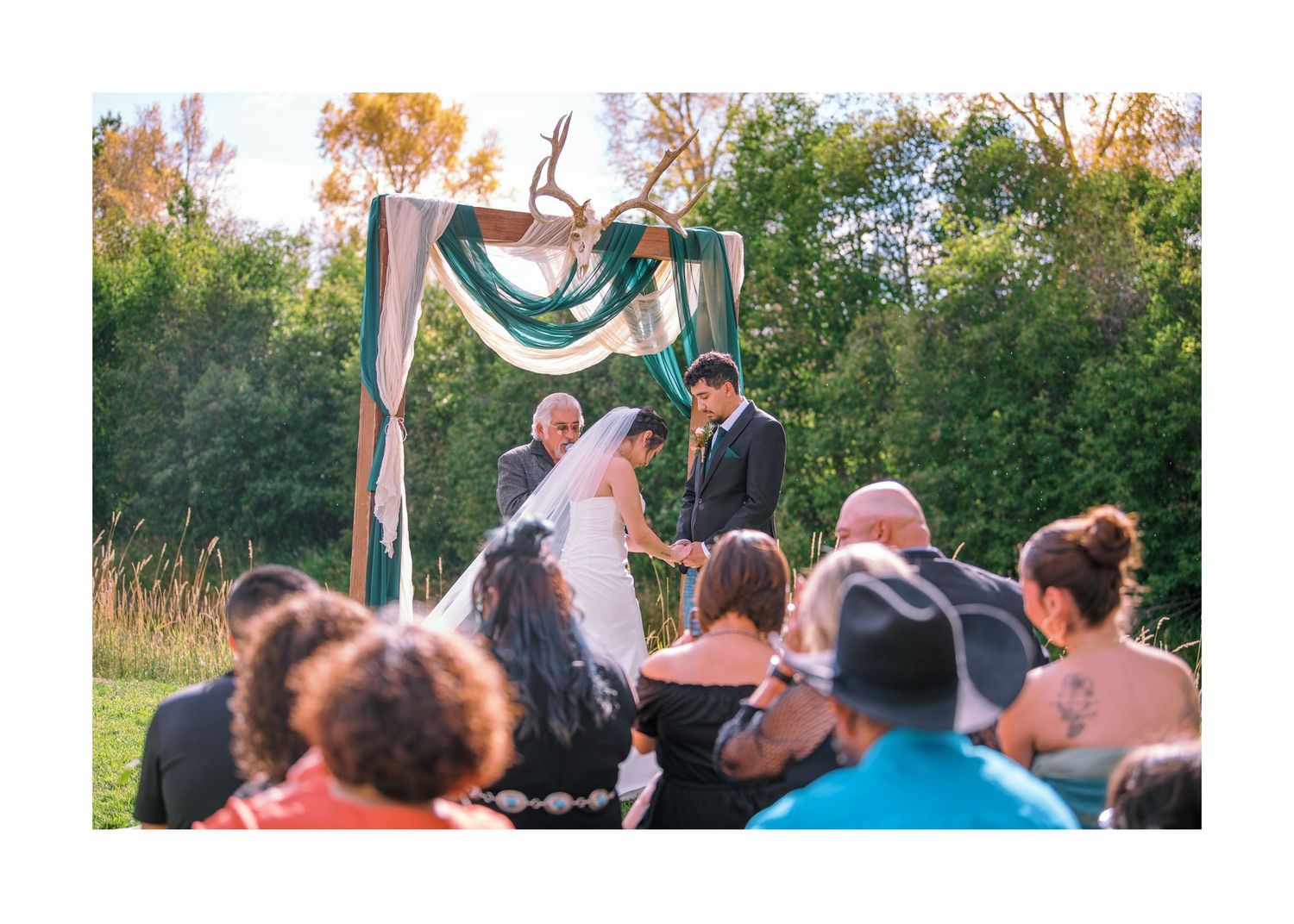 Wedding guests standing in a semicircle during an outdoor fall ceremony.