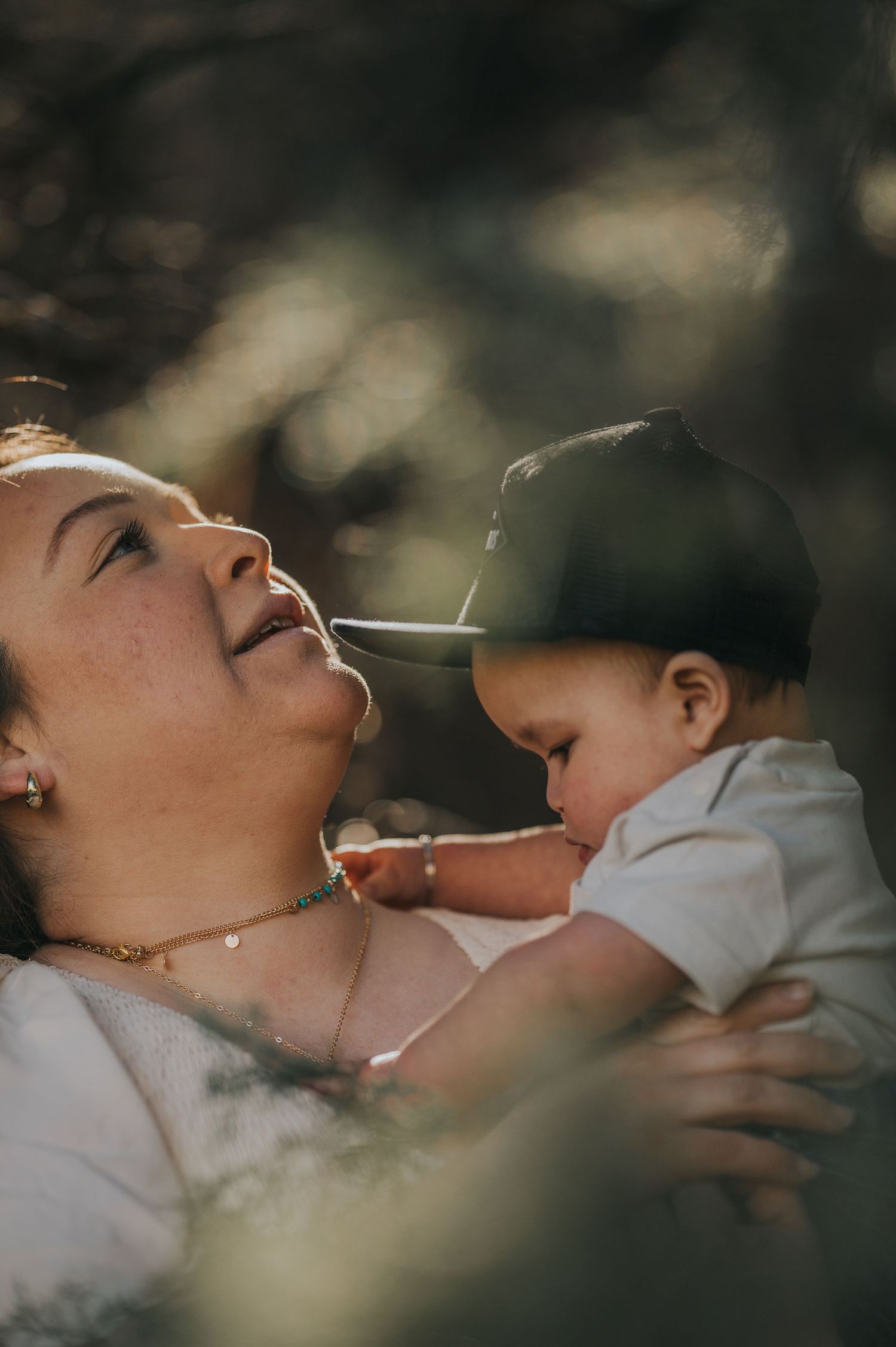 Candid shot of mother and baby under the canopy of pine trees — heartfelt storytelling by Quiet Light by The Amoras.