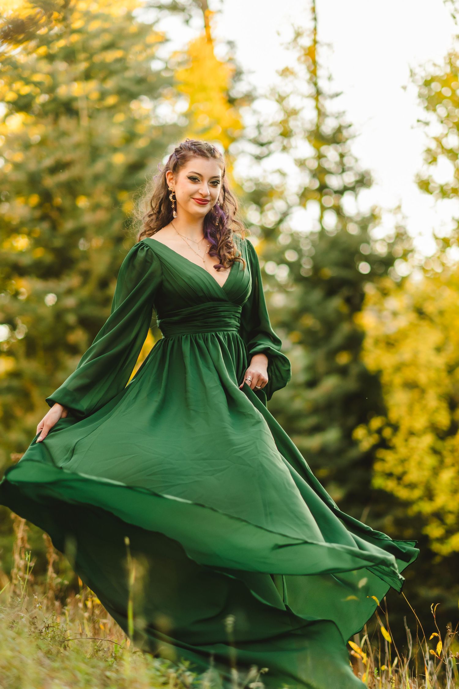 A flowing emerald green dress twirls gracefully in a golden sunlit forest setting.