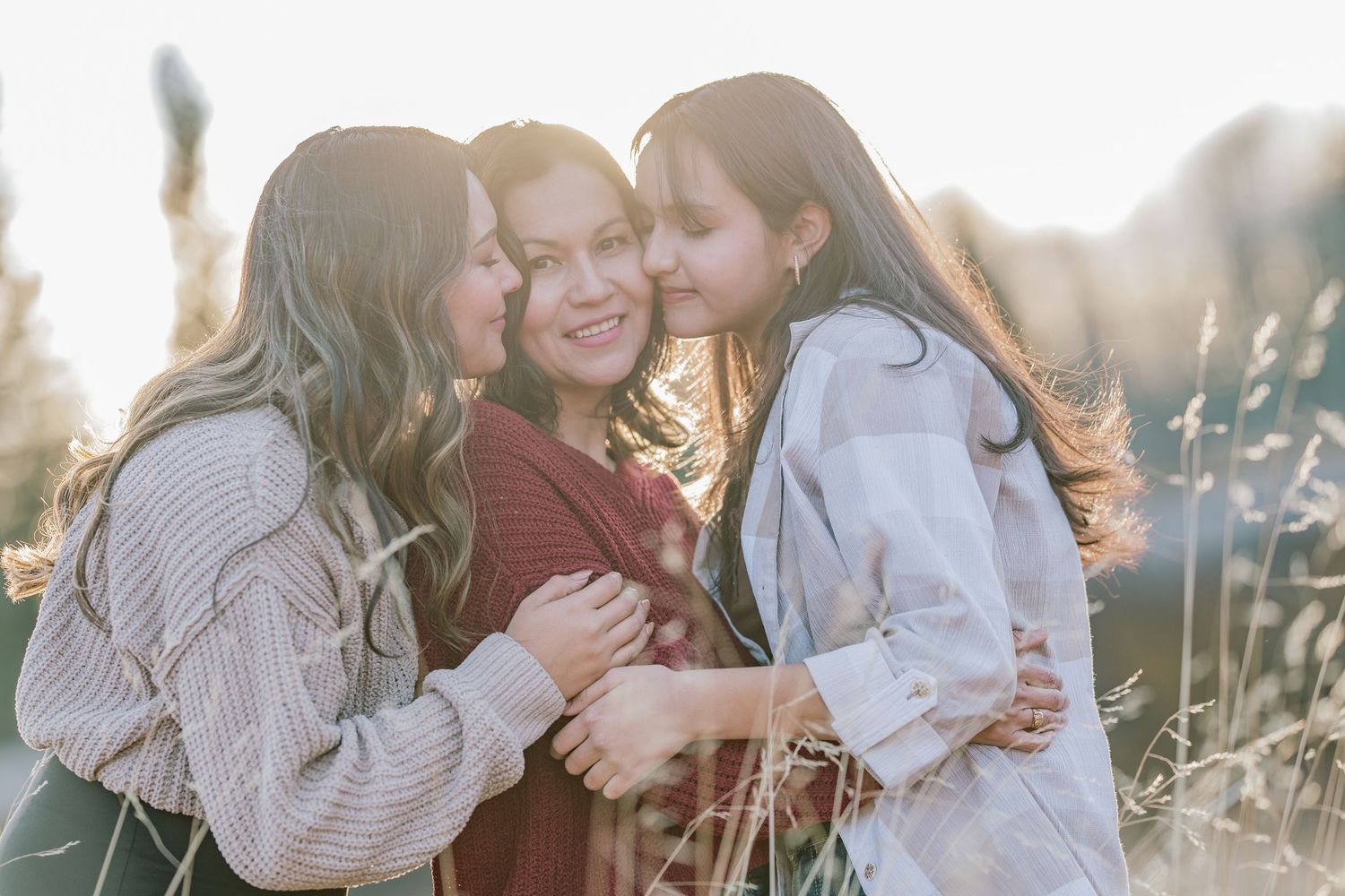 Family embraces during golden hour sunset photo session in a field.