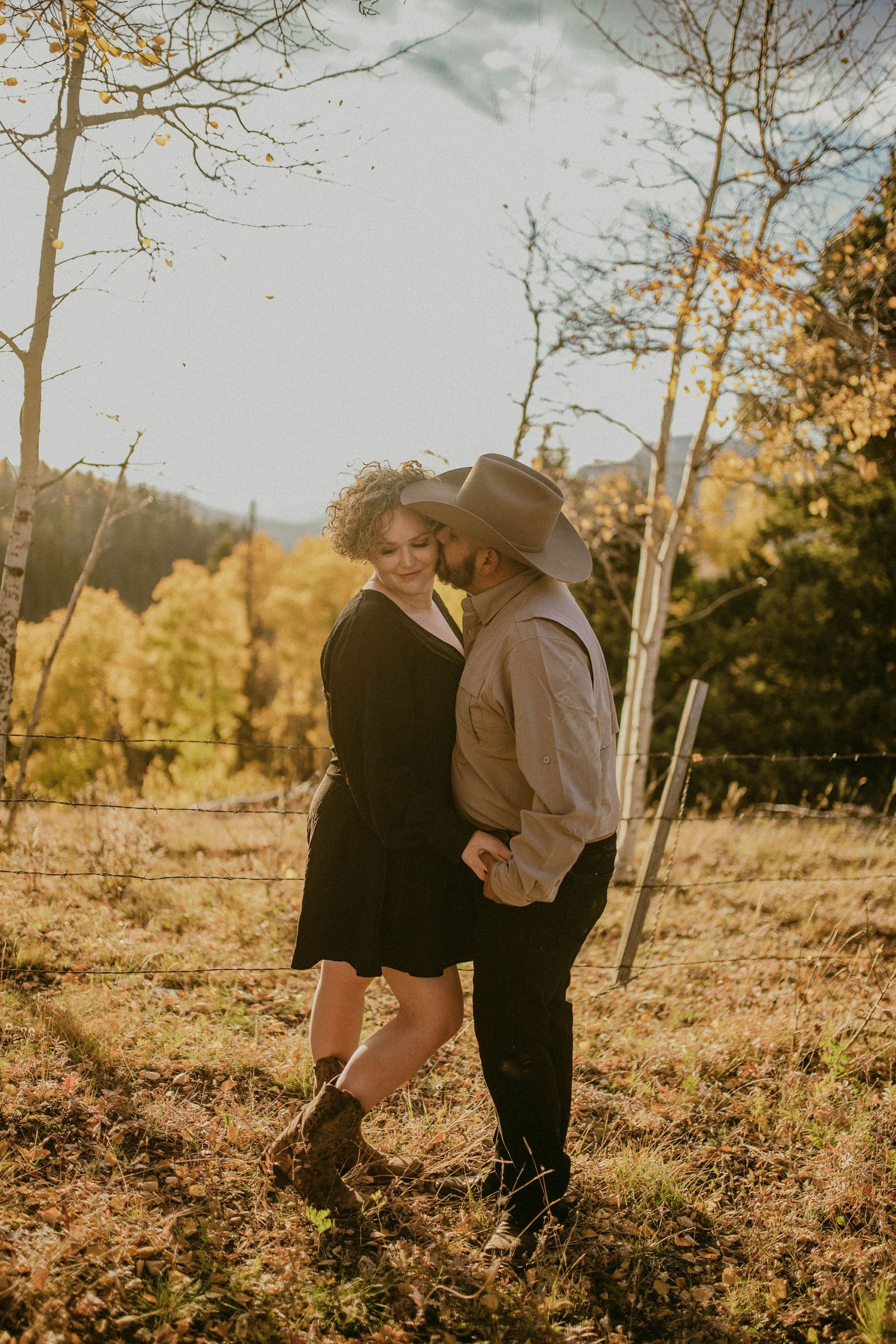 Couple shares intimate moments in a sun-drenched autumn forest with yellow leaves and birch trees.
