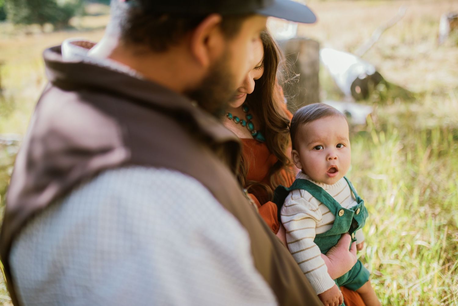 Family outdoor portrait session in natural grassland setting with rustic elements.
