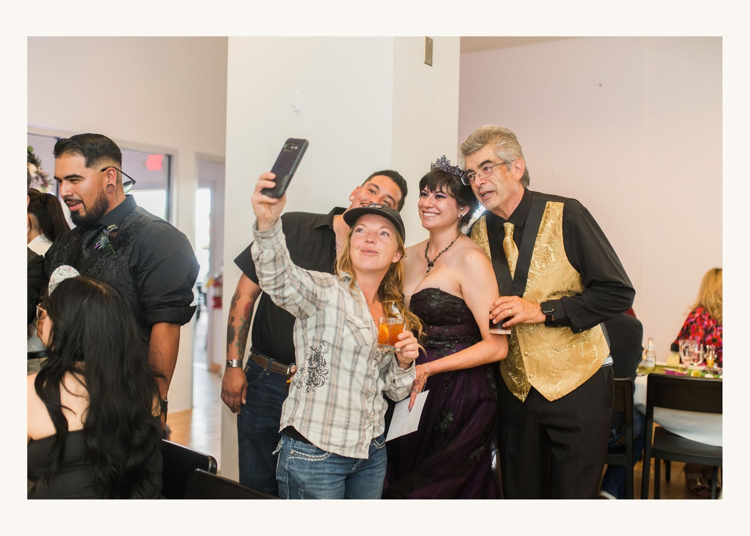 Group of friends taking a selfie at a formal party event, wearing festive costumes and holding drinks.