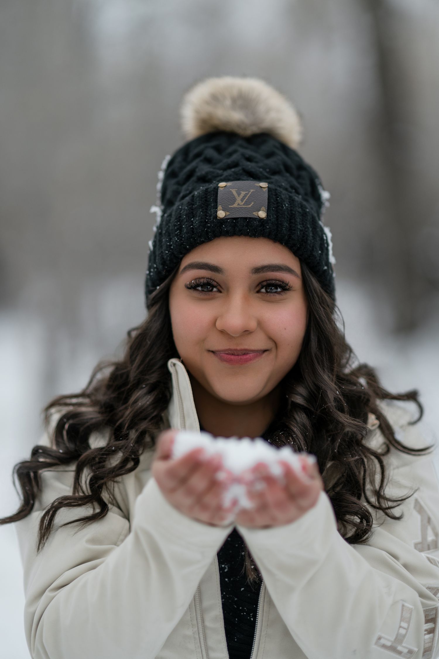 A person in winter attire blows snow from their hands in a series of playful outdoor portraits.