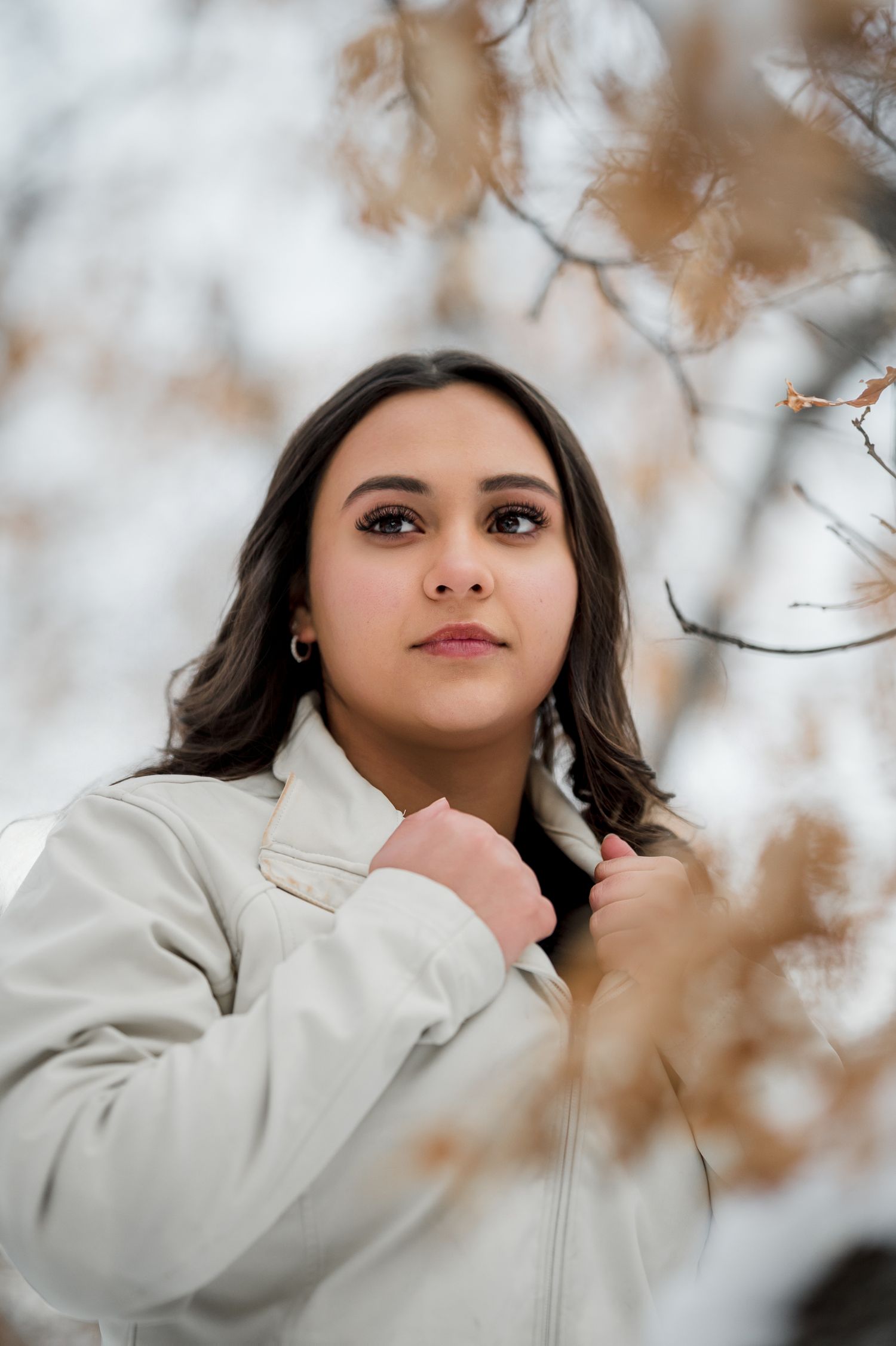 Artistic outdoor photography with a cream colored jacket and soft bokeh effect from autumn foliage.
