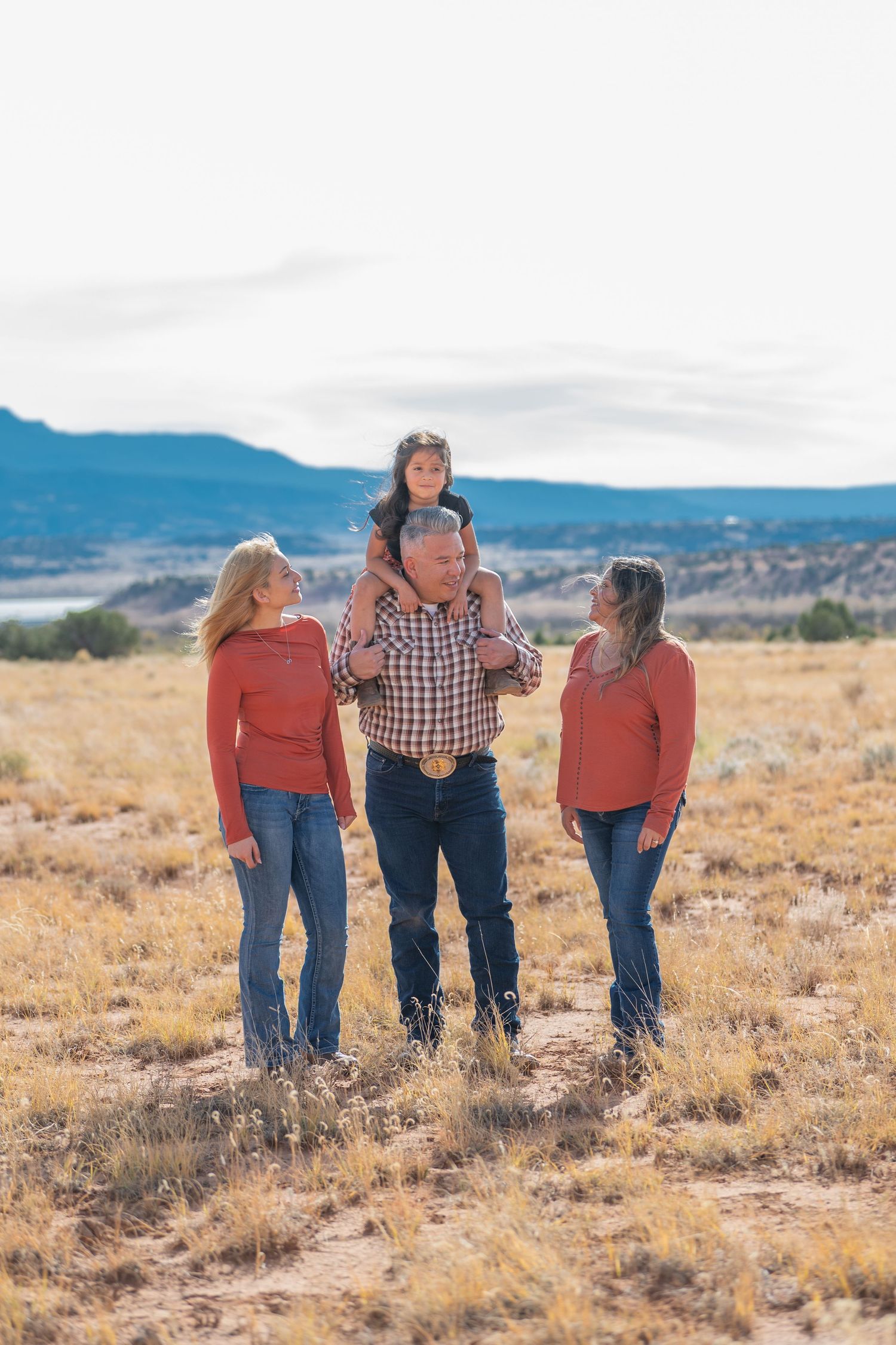 Family enjoying time together in an open field with mountains in the background on a sunny autumn day.