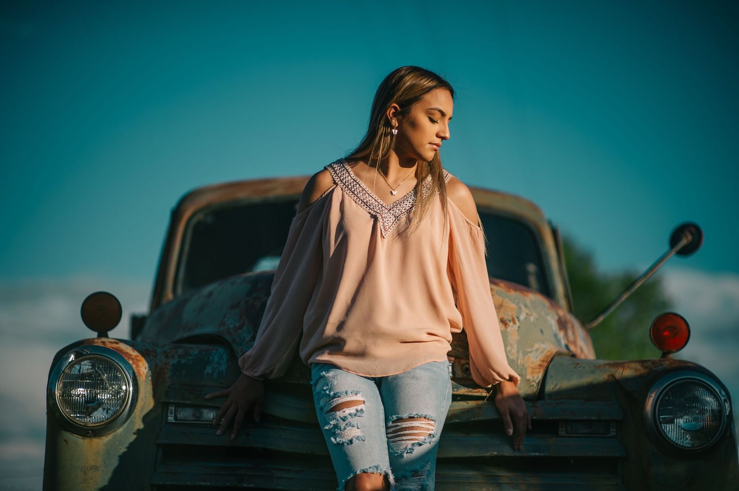 Person in casual wear poses against retro truck with turquoise sky background.
