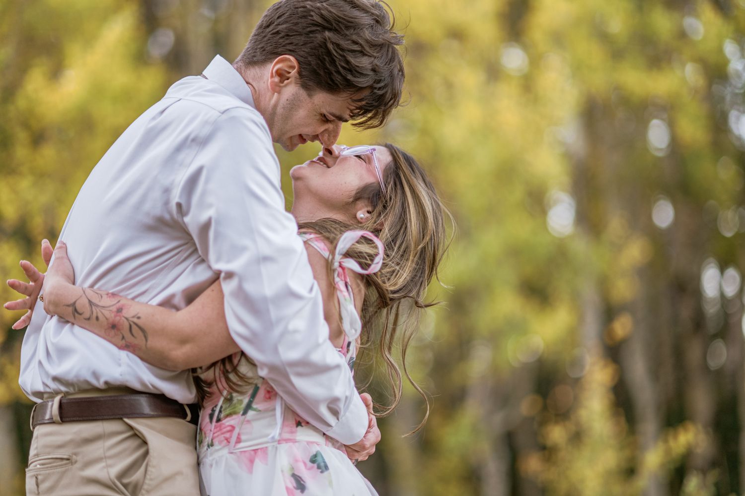 Fiance lifts her for a kiss among autumn trees during a fall engagement session in Chama, NM.