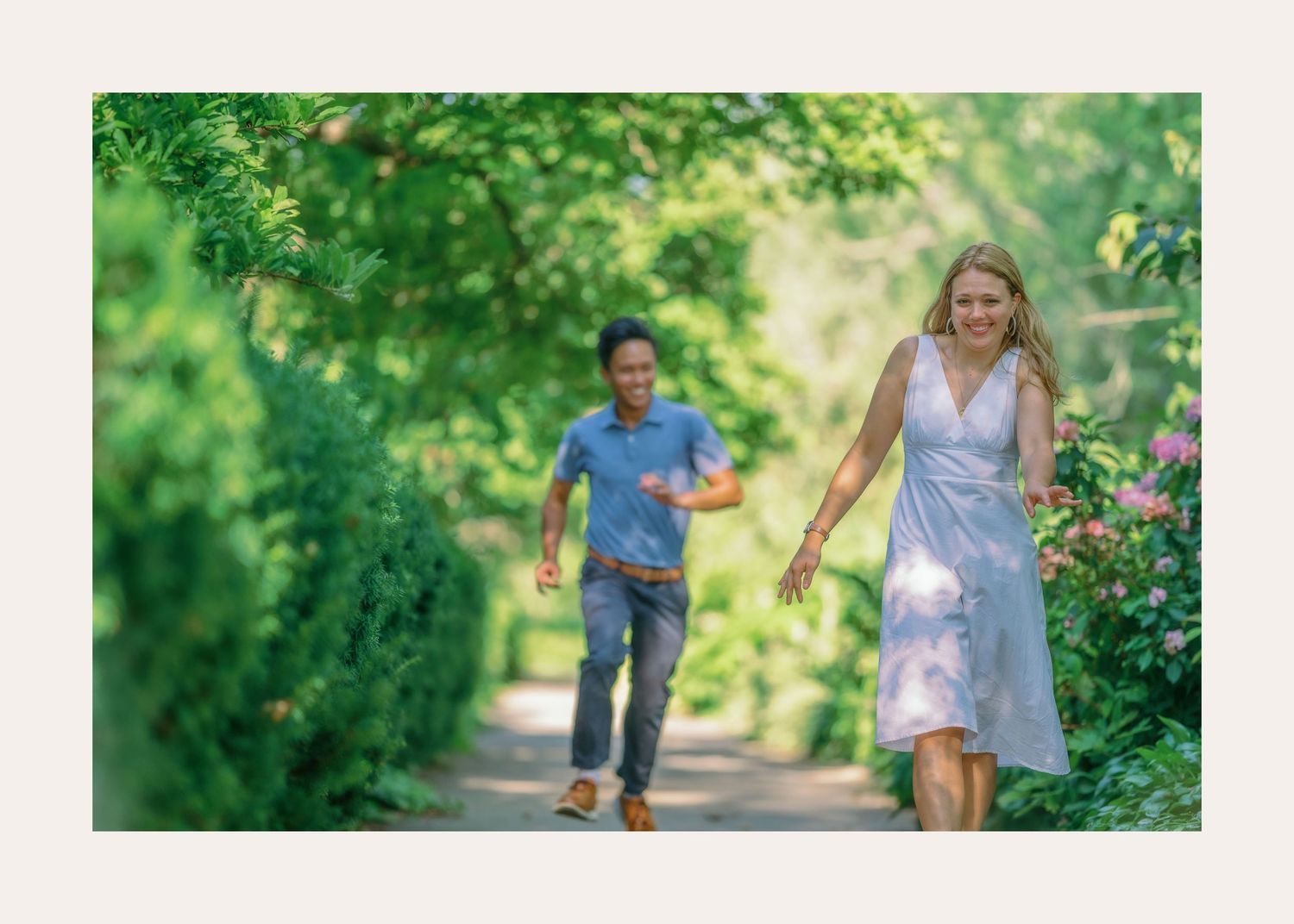 Two people enjoy running together along a lush green park path on a sunny summer day.