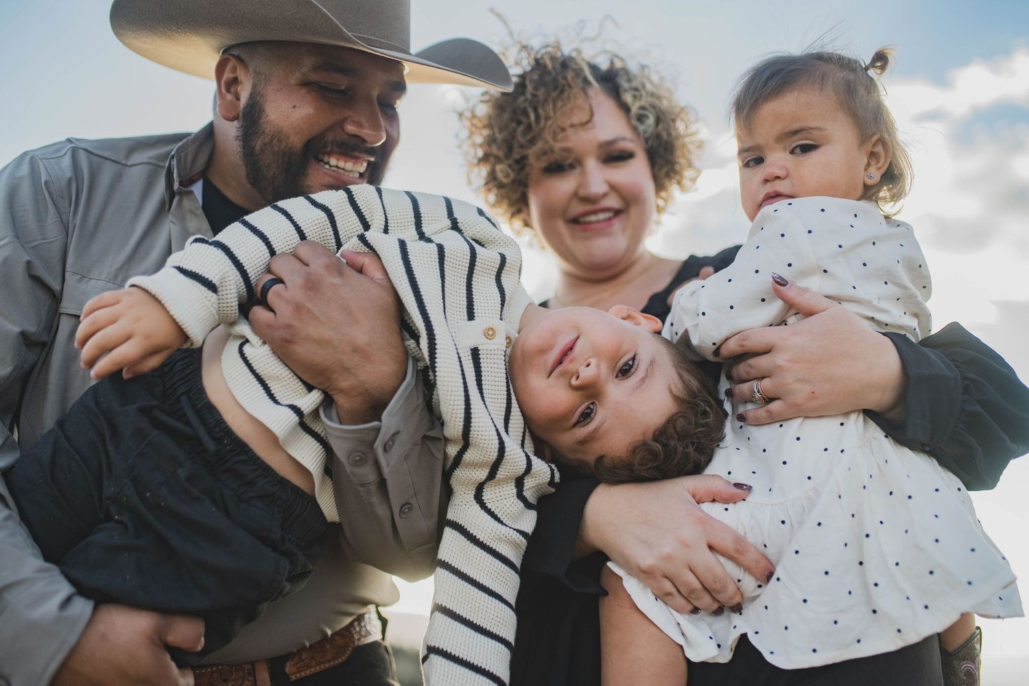 Joyful autumn family photo with mom, dad, and two toddlers — captured in warm light by Quiet Light by The Amoras.